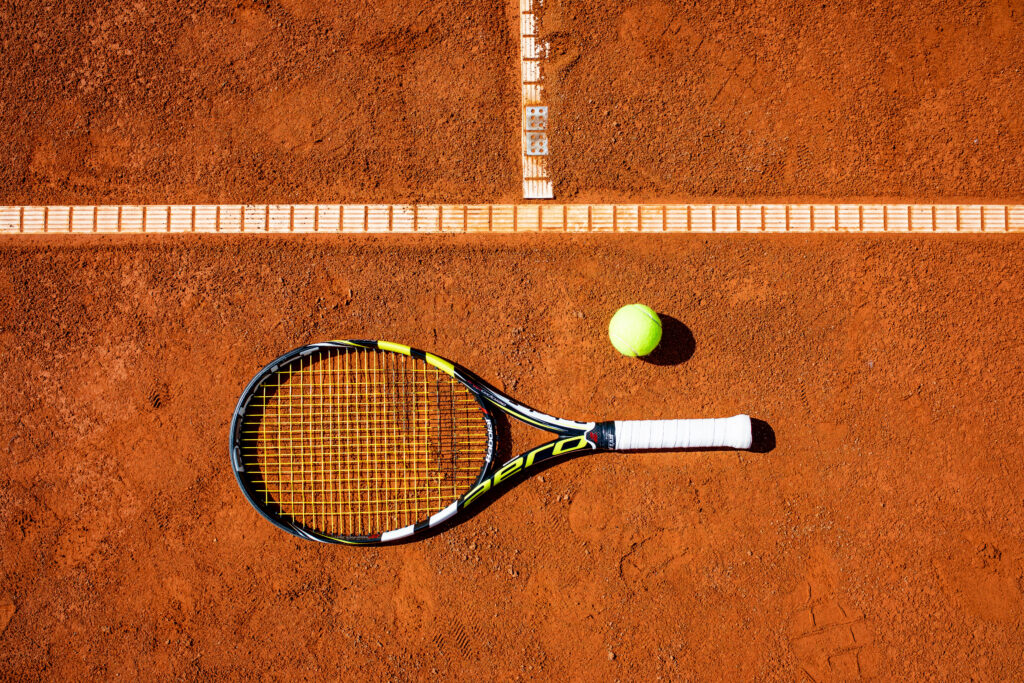 Tennisschläger und Ball auf Sandplatz