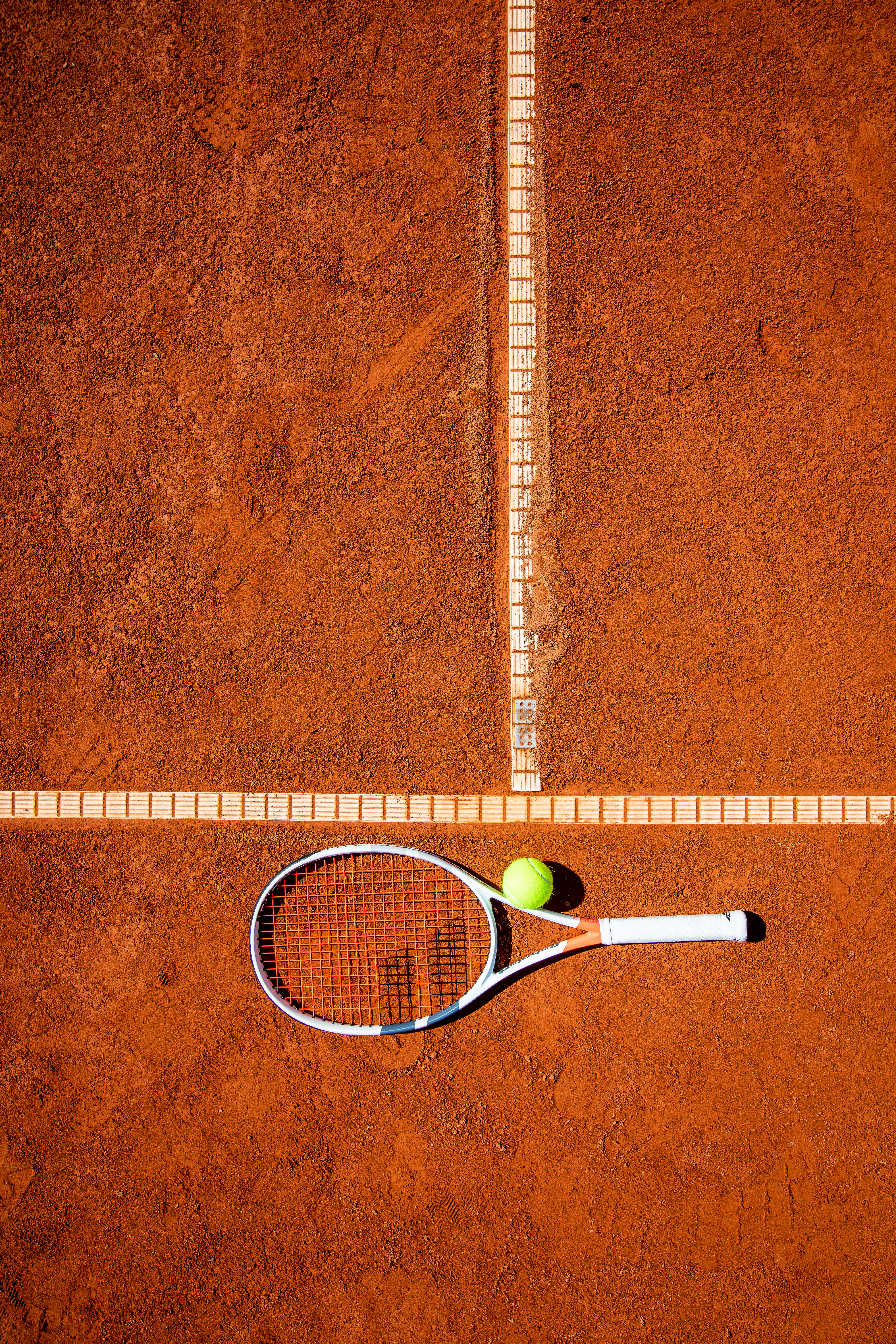 Tennisschläger und Ball auf rotem Sandplatz