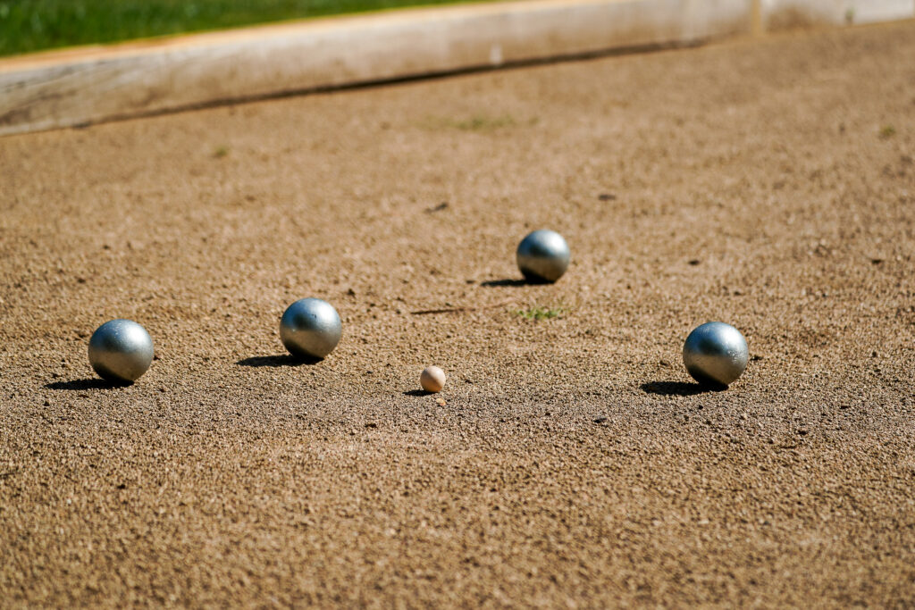 Pétanque-Kugeln auf sandigem Spielfeld mit Zielkugel
