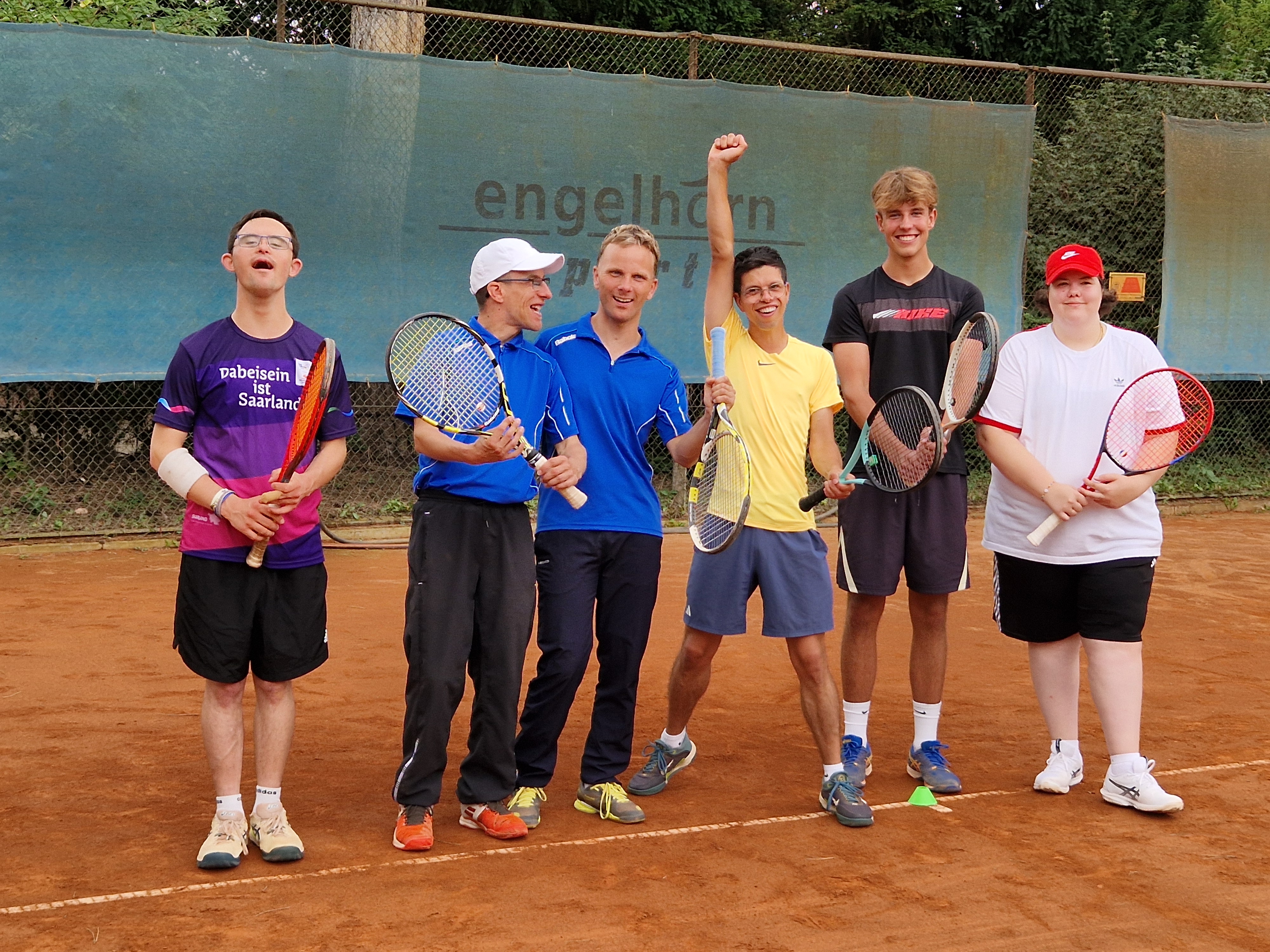 Sechs Tennisspieler mit Schlägern auf Sandplatz