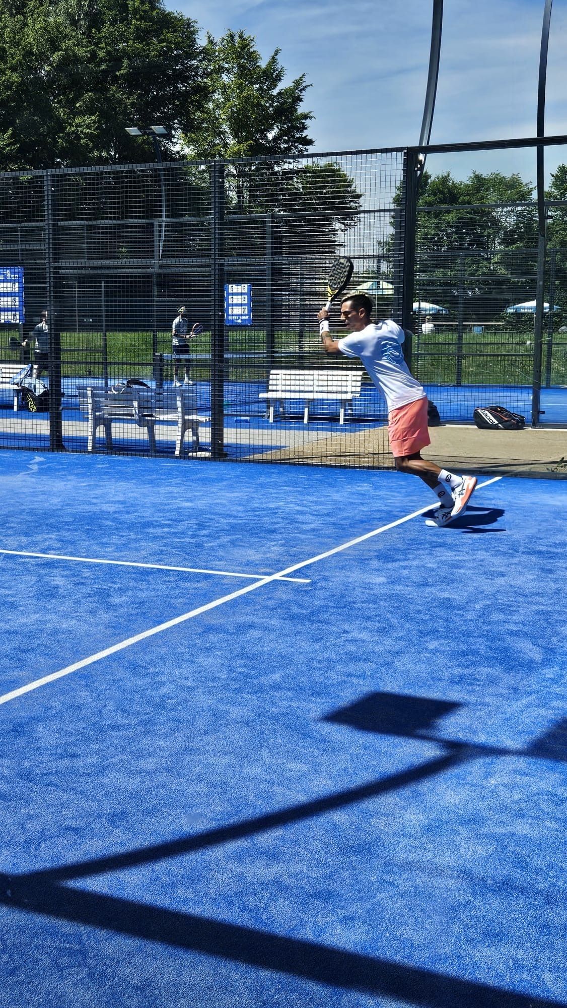 Mann spielt Padel auf blauem Outdoor-Court