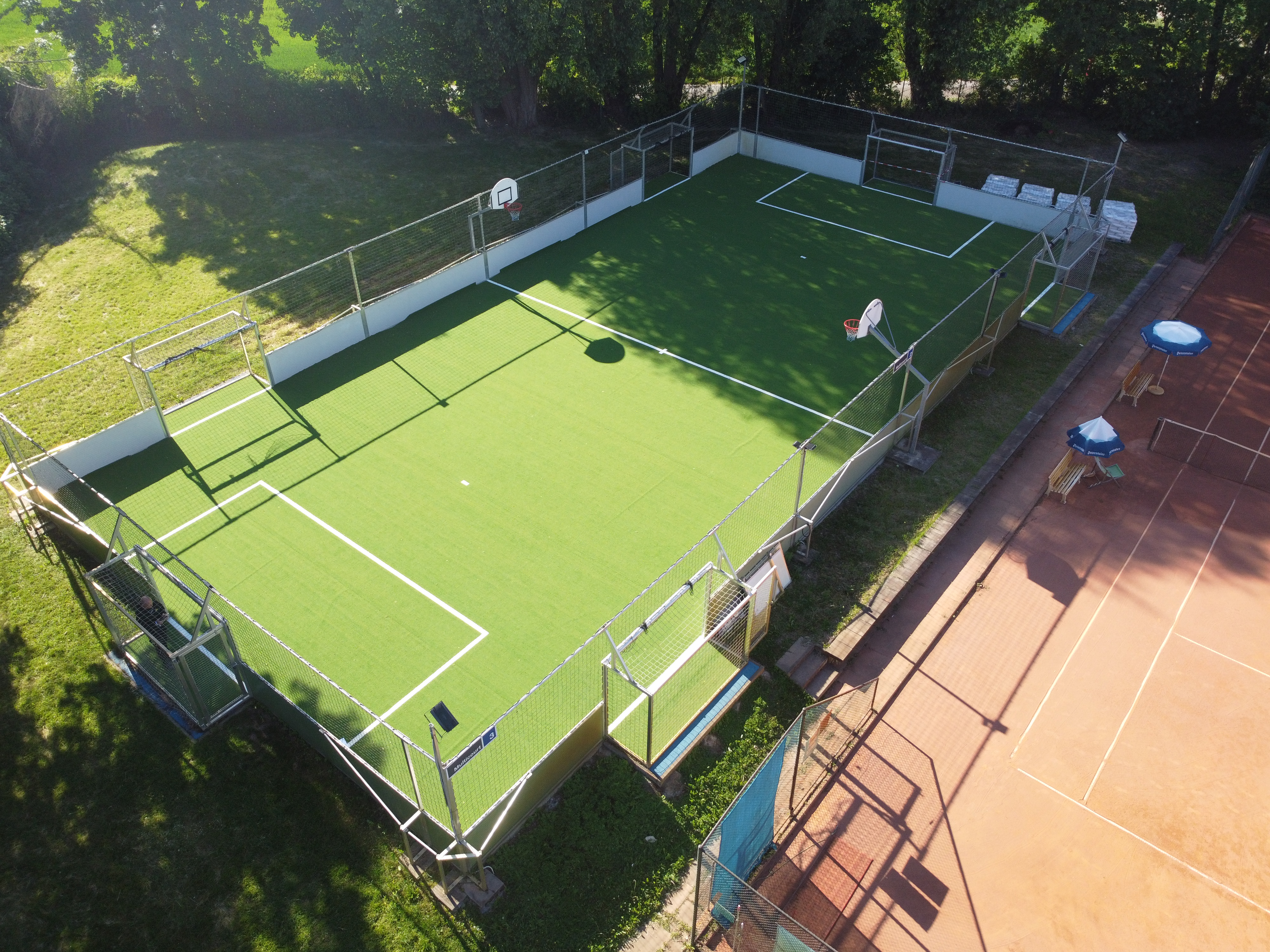 Kleiner Kunstrasen-Sportplatz mit Basketballkörben und Toren