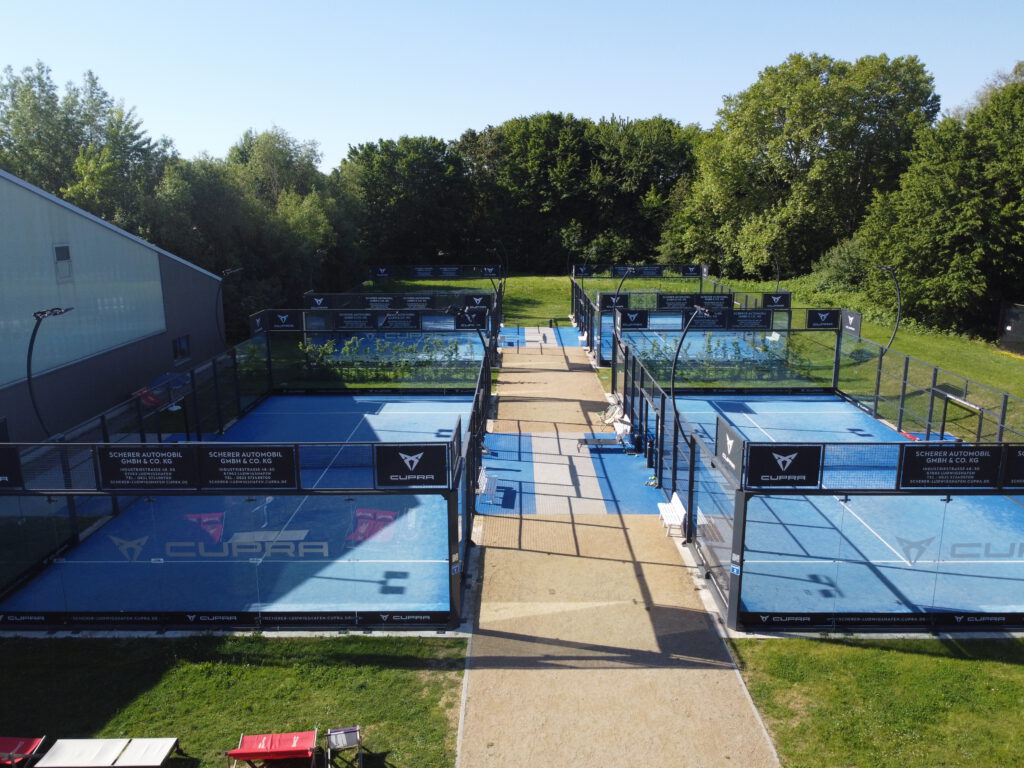 Mehrere Padelplätze im Freien mit Glaswänden