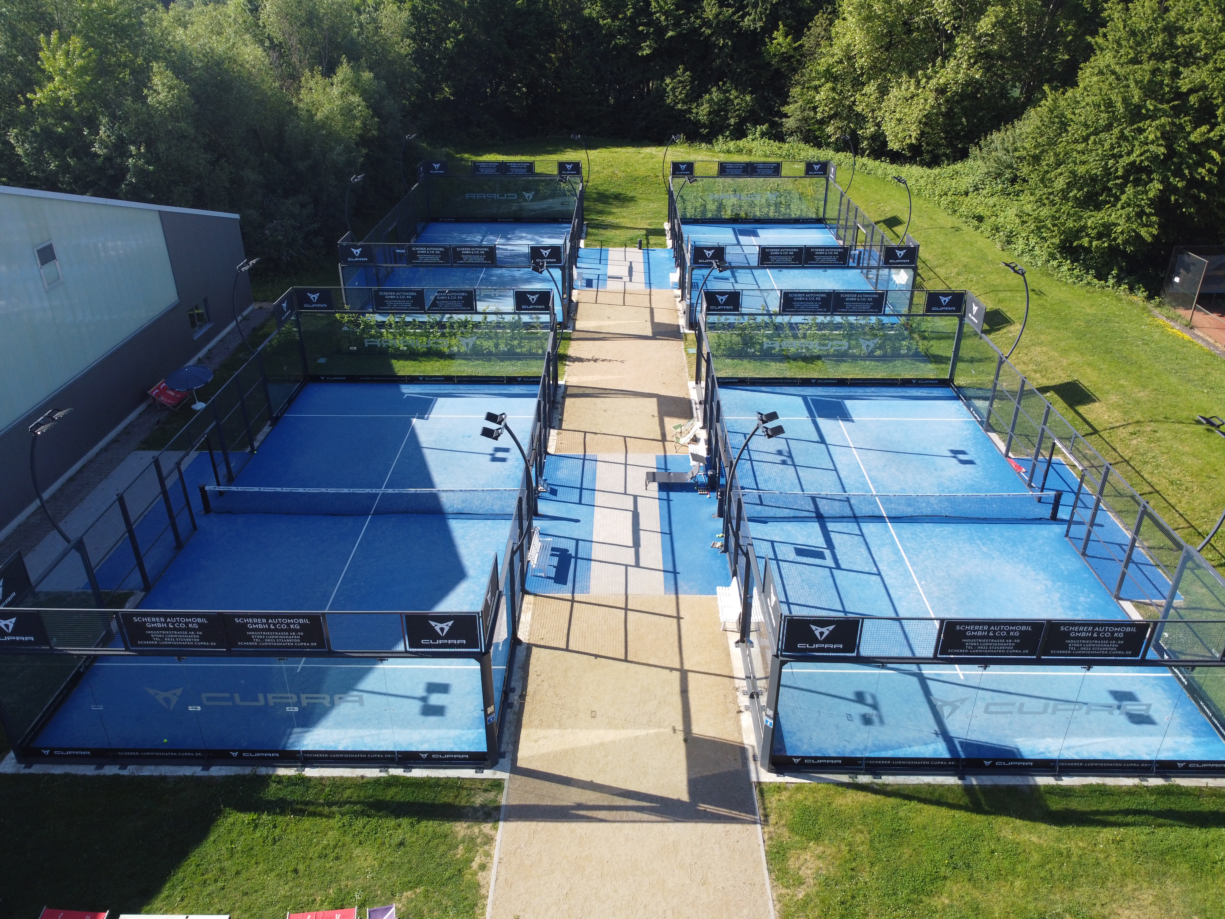 Luftaufnahme moderner Padelplätze im Grünen