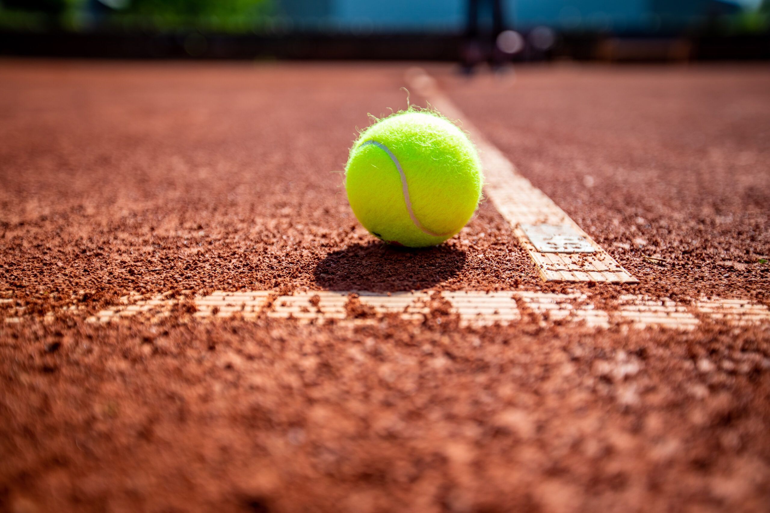 Tennisball auf rotem Sandplatz nahe Linie