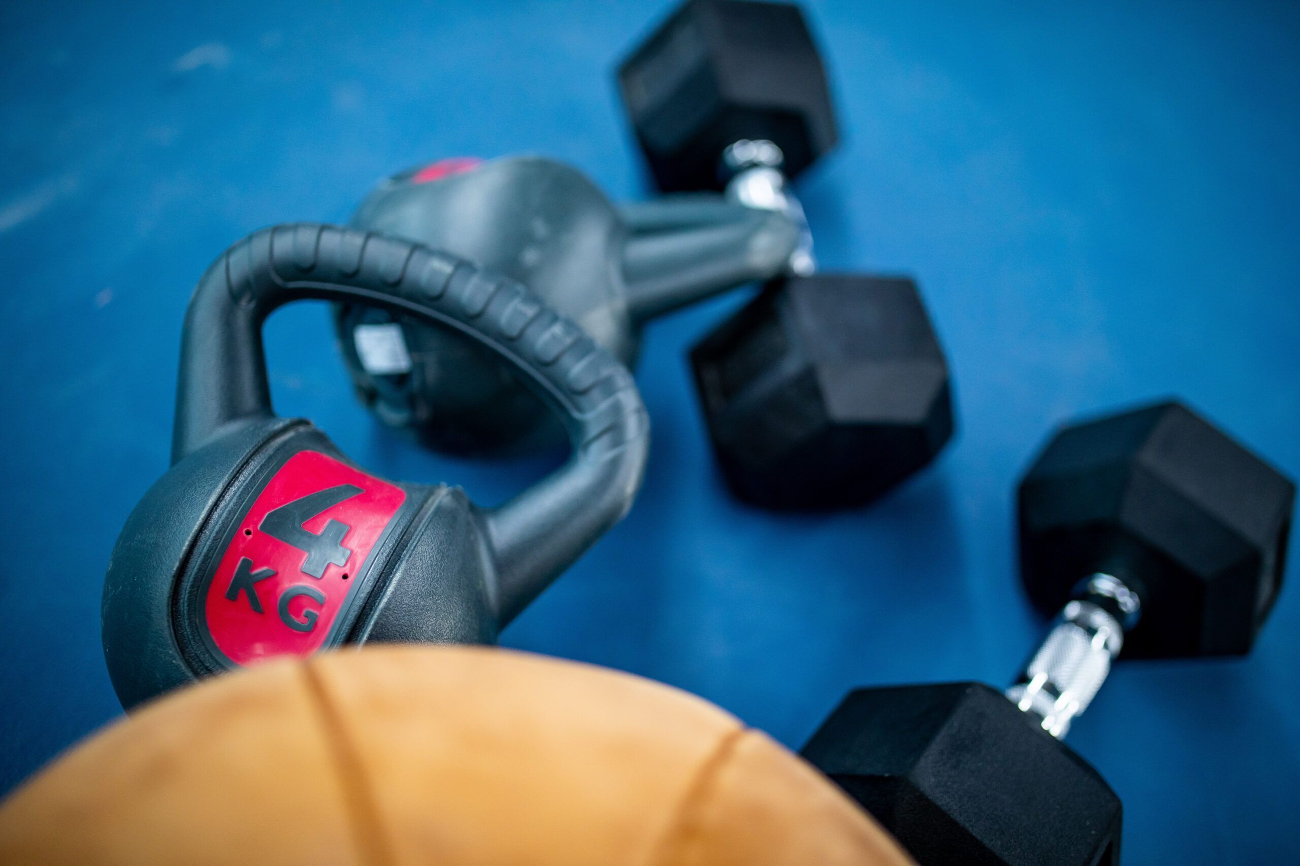 Kettlebell, Hanteln und Basketball auf blauem Boden