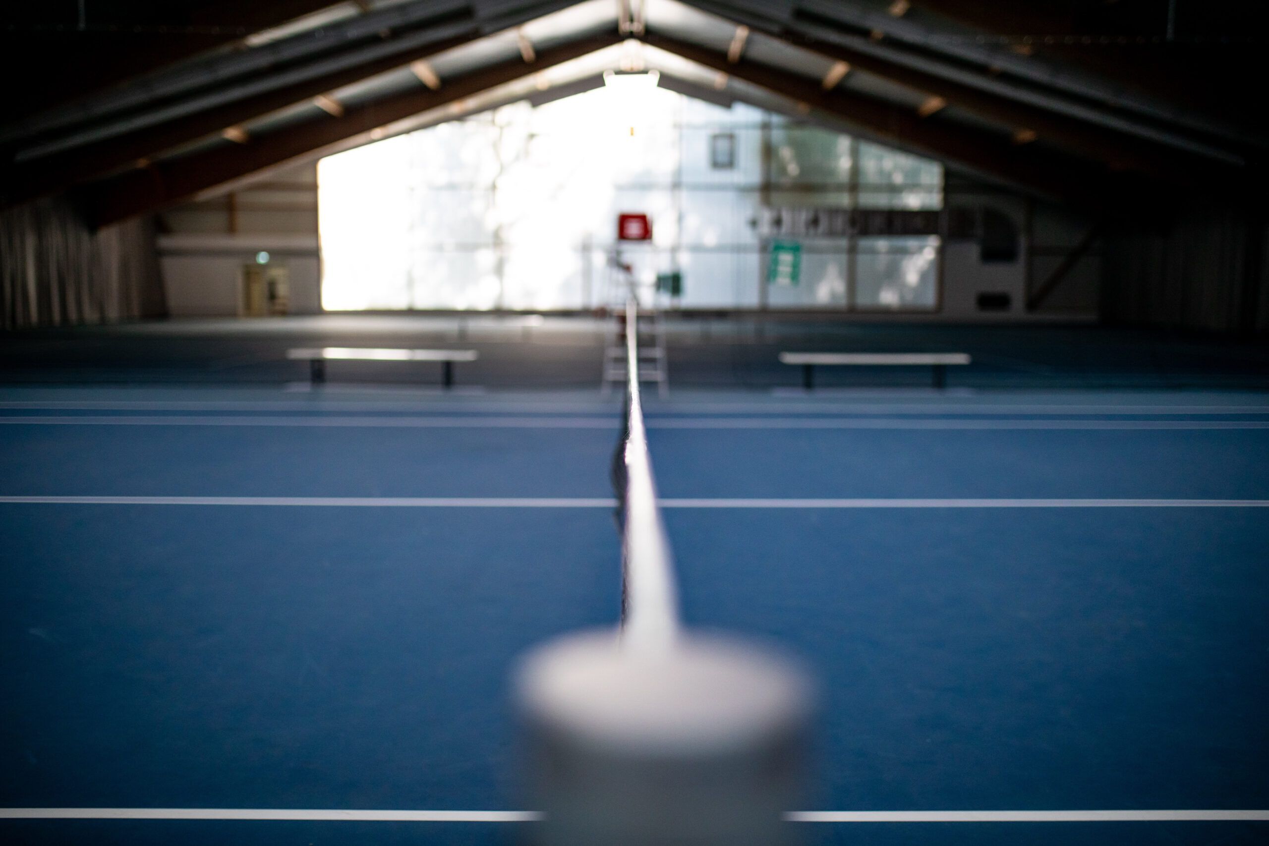 Tennishalle mit Netz in Zentralperspektive