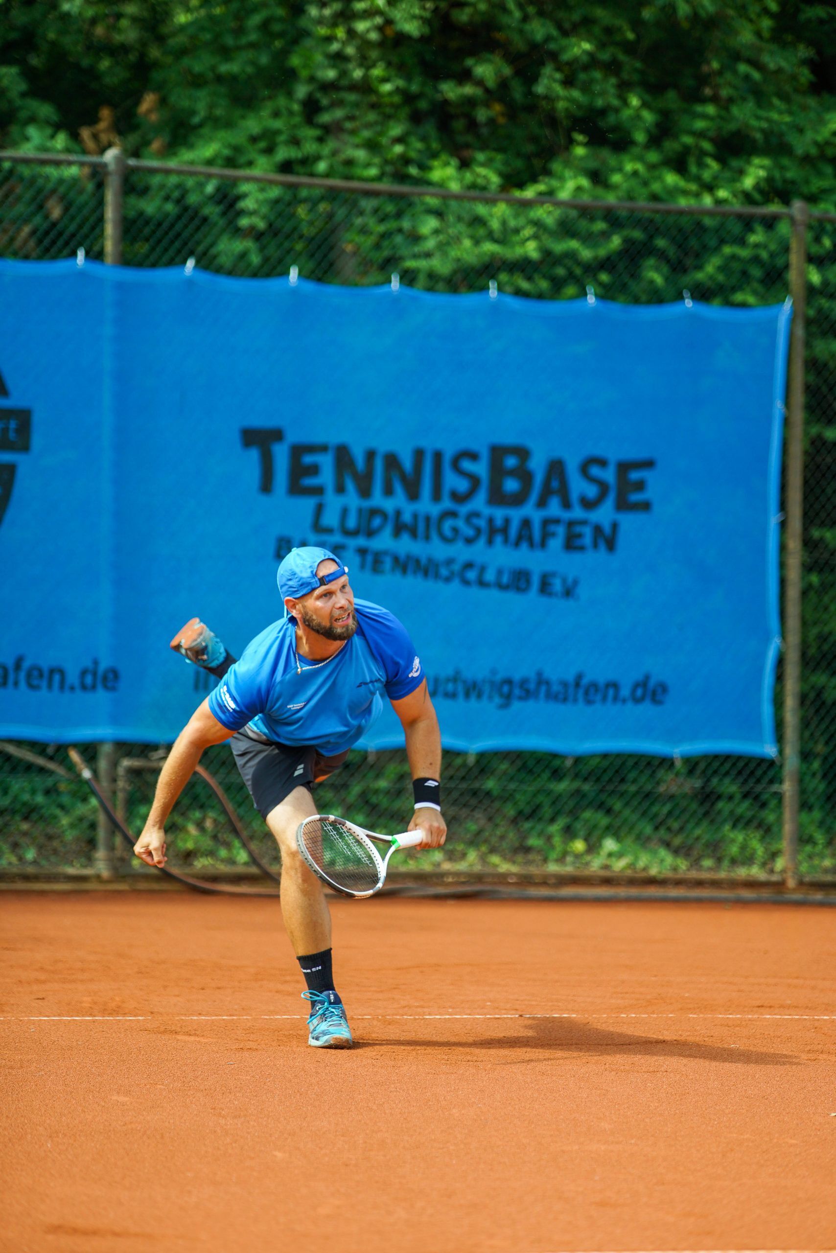 Tennisspieler beim Aufschlag auf Sandplatz