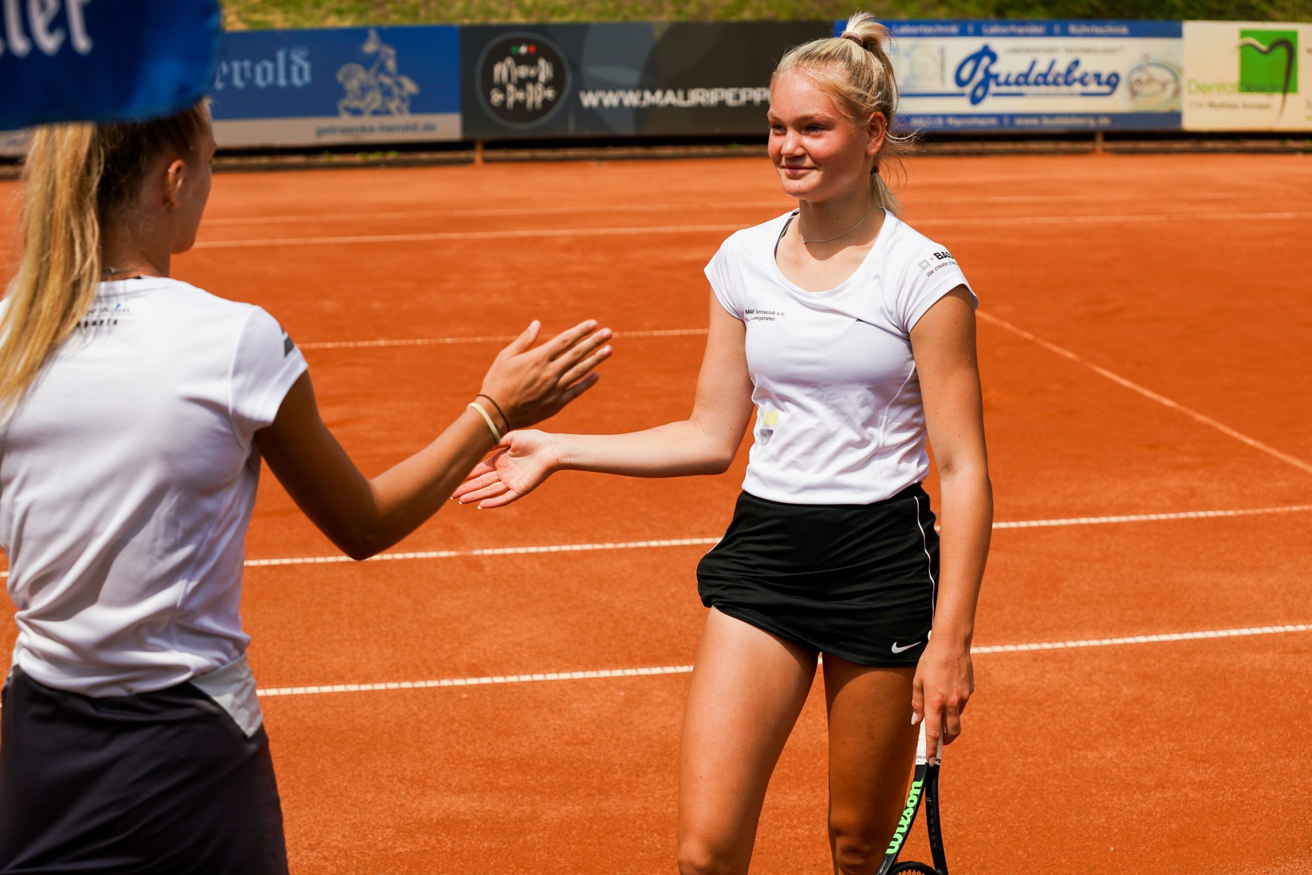Zwei Tennisspielerinnen beim Handschlag auf Sandplatz