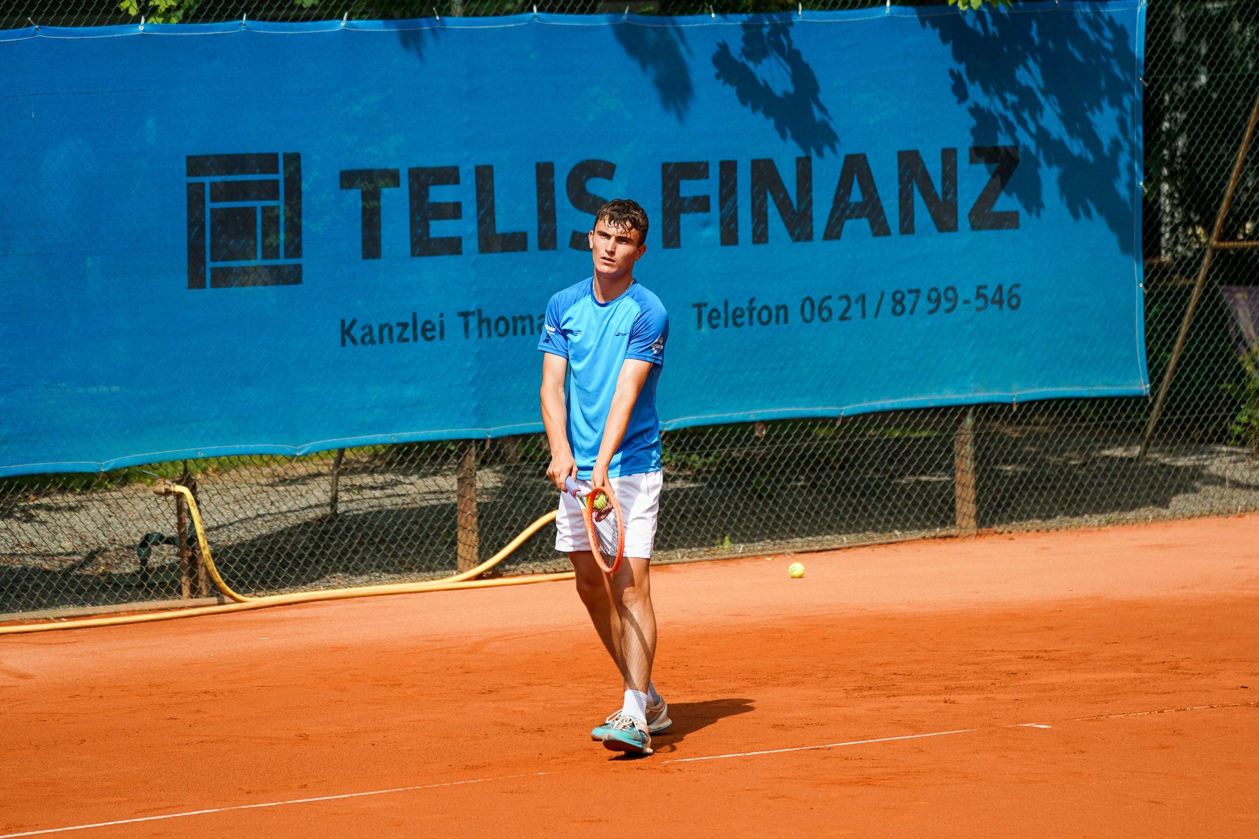Tennisspieler auf Sandplatz beim Rückhand-Schlag