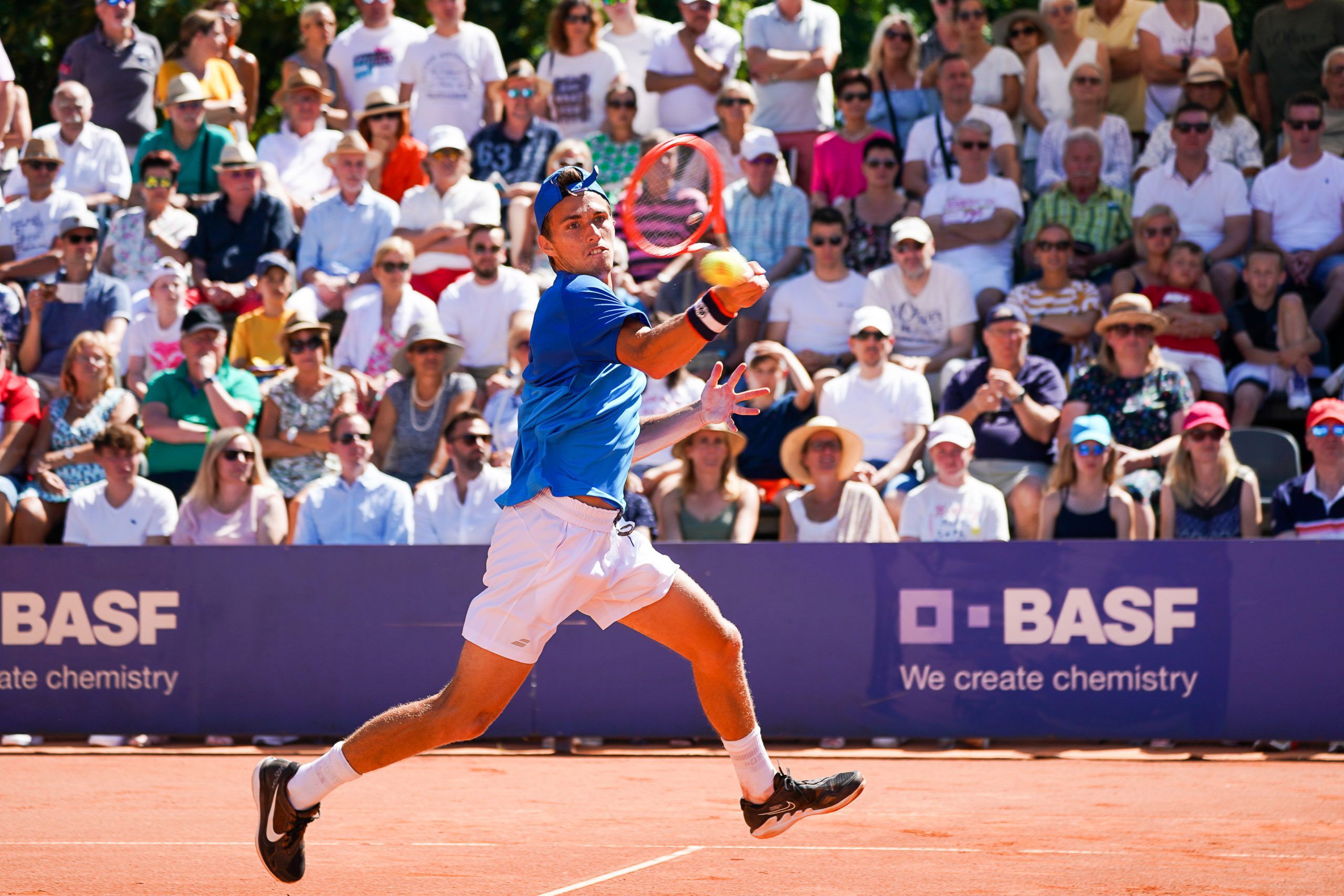 Tennisspieler schlägt Vorhand auf Sandplatz