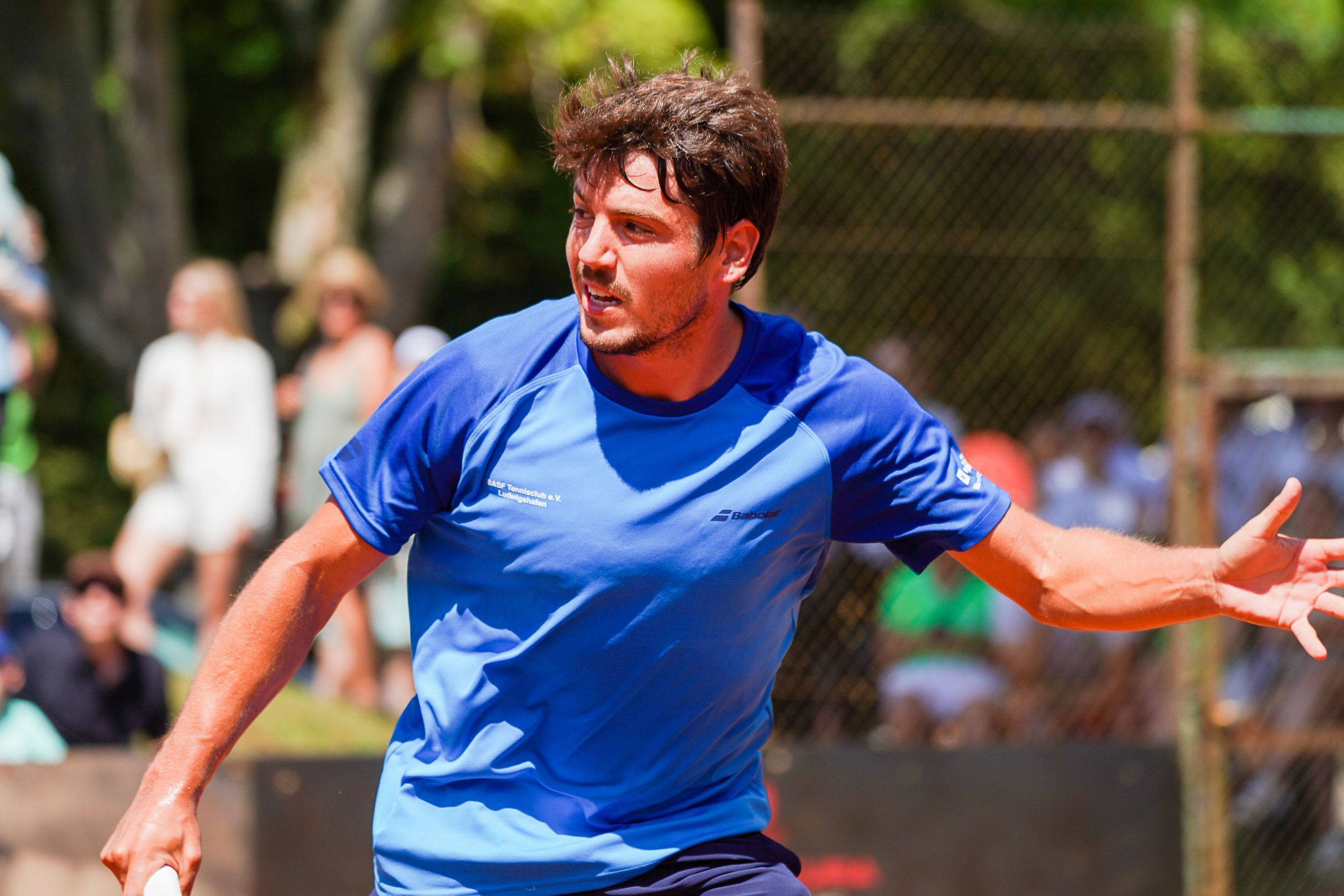 Tennisspieler im blauen Shirt auf Sandplatz