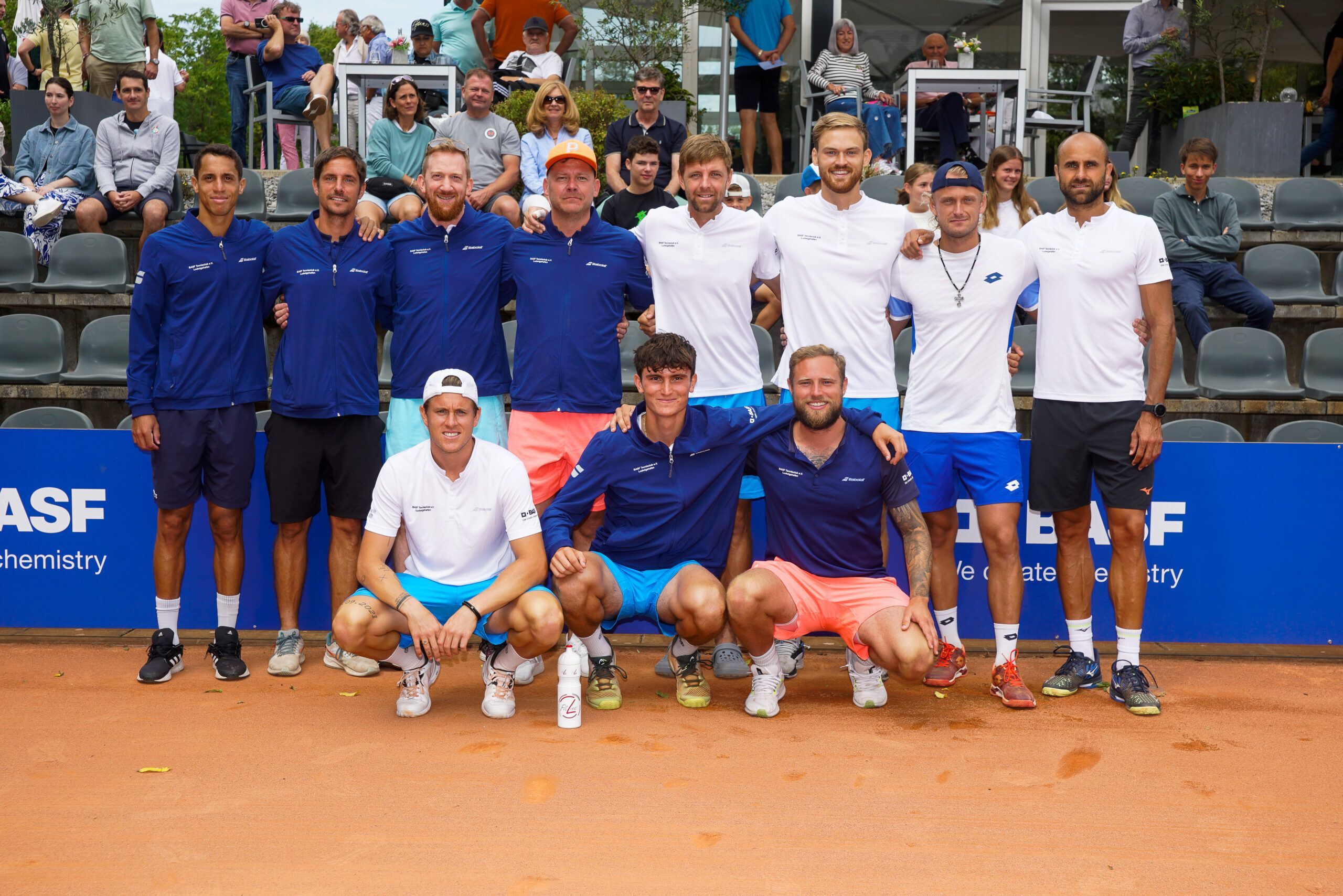Tennisspieler posieren gemeinsam auf Sandplatz
