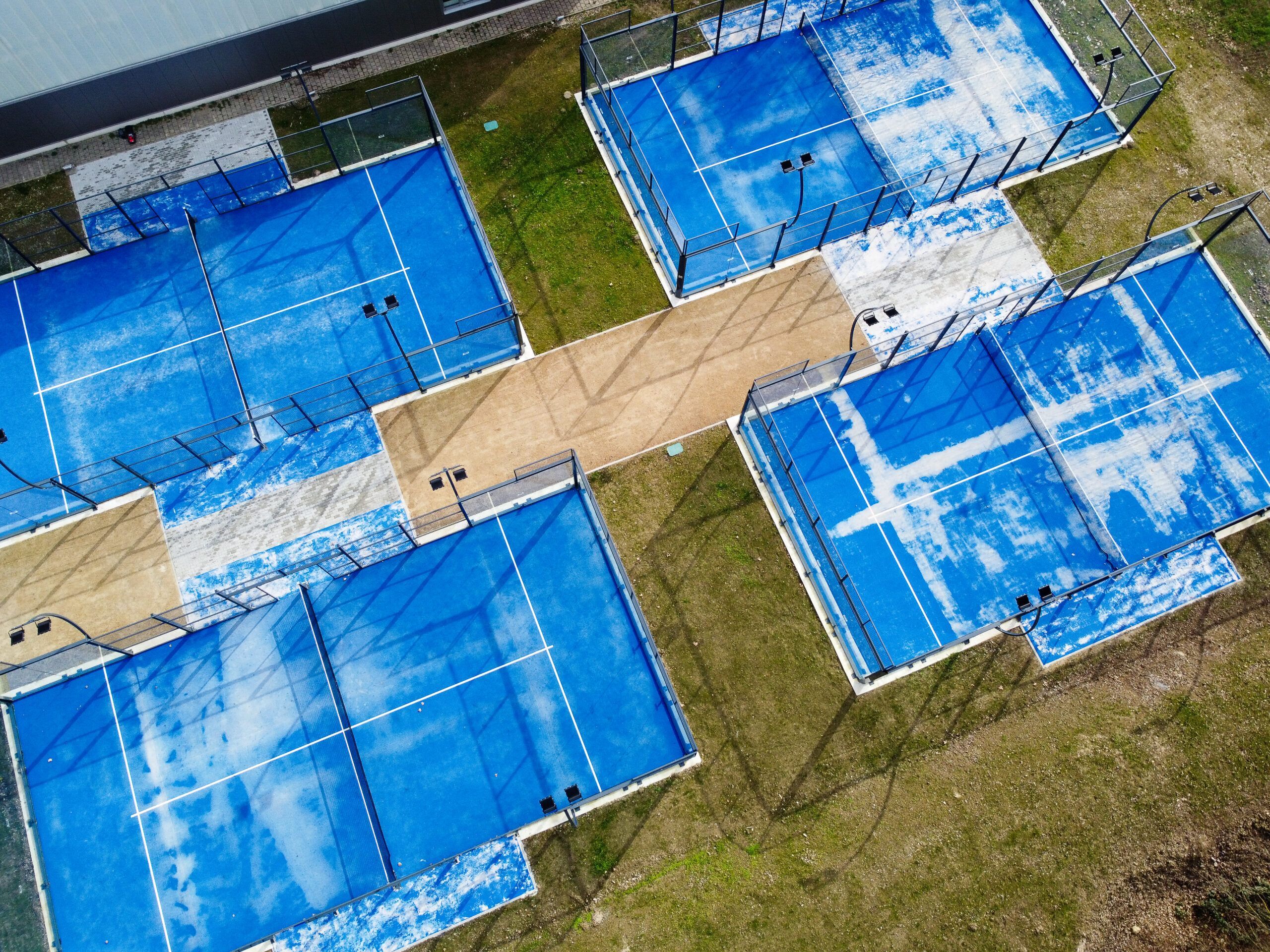 Luftaufnahme mehrerer blauer Padelplätze im Freien