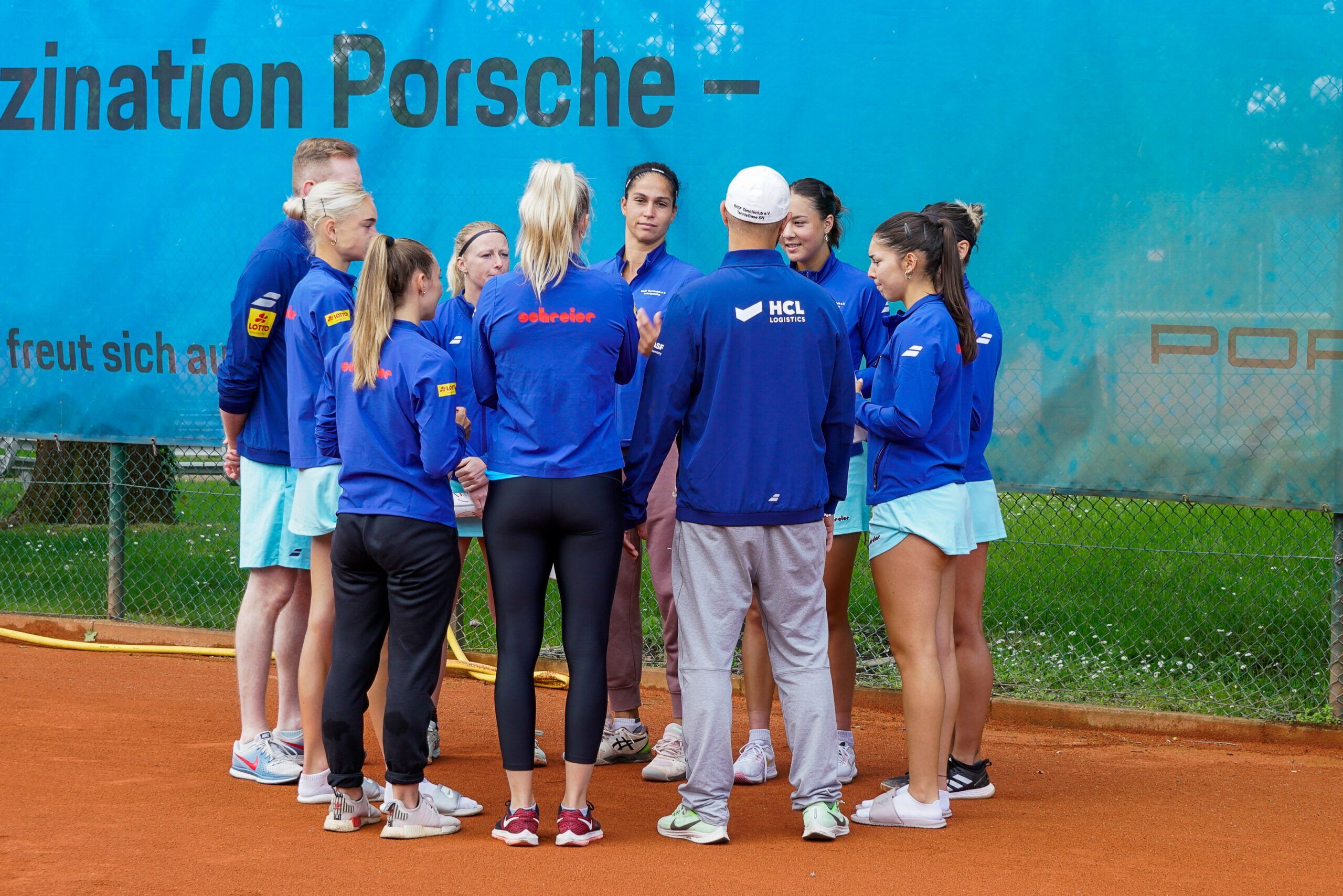 Tennisteam im Kreis auf Sandplatz