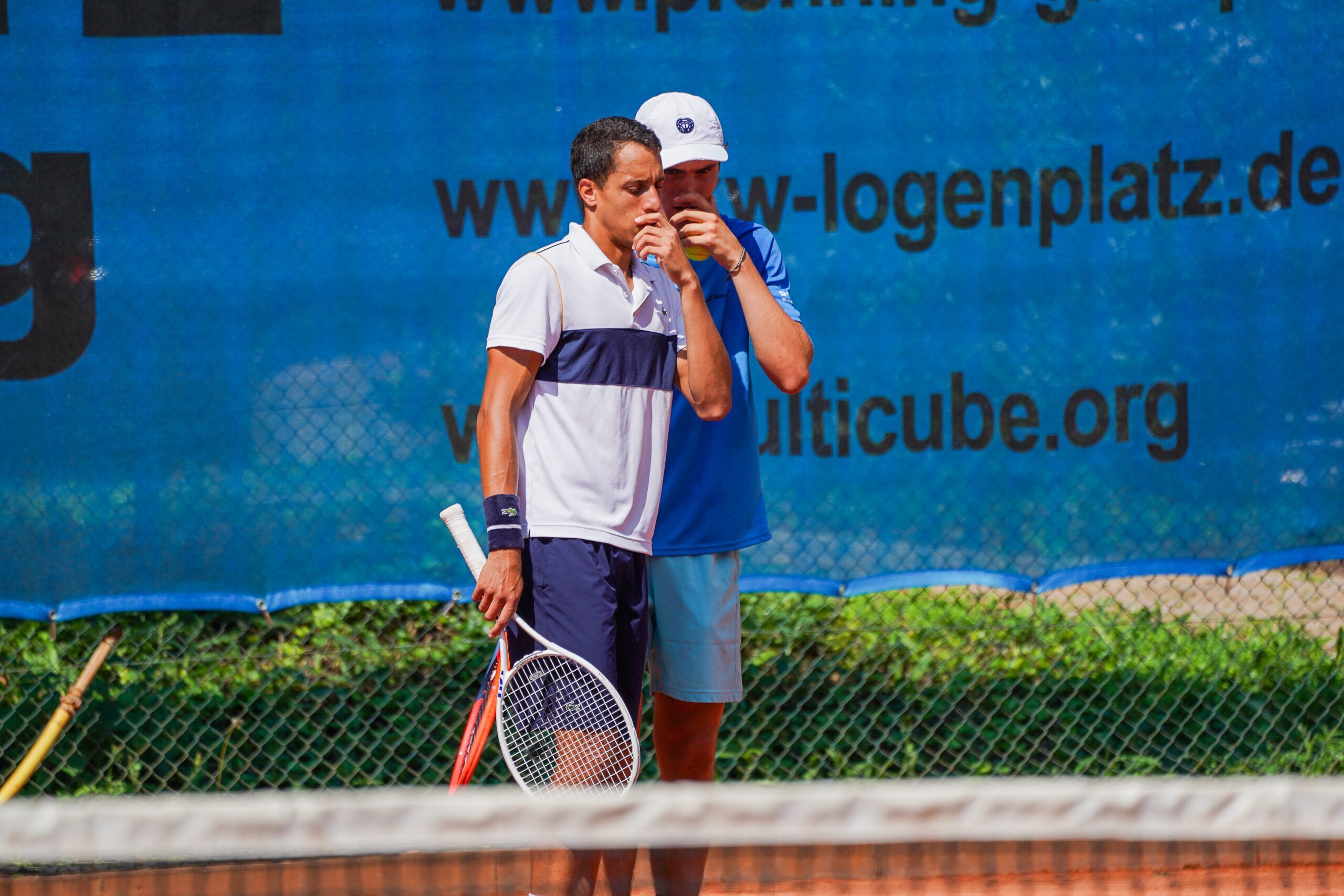 Zwei Tennisspieler beraten sich auf Sandplatz