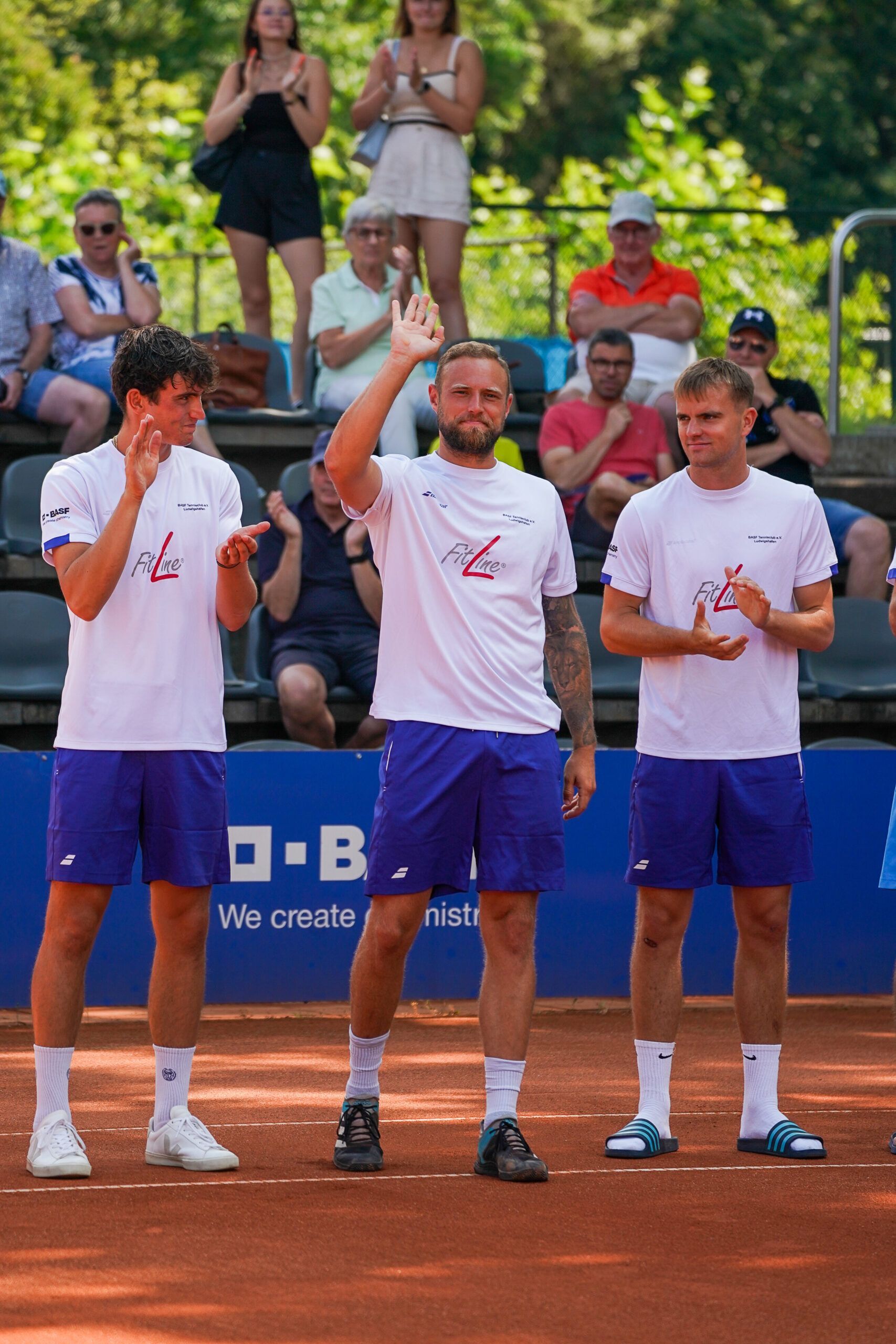 Drei Tennisspieler winken auf Sandplatz