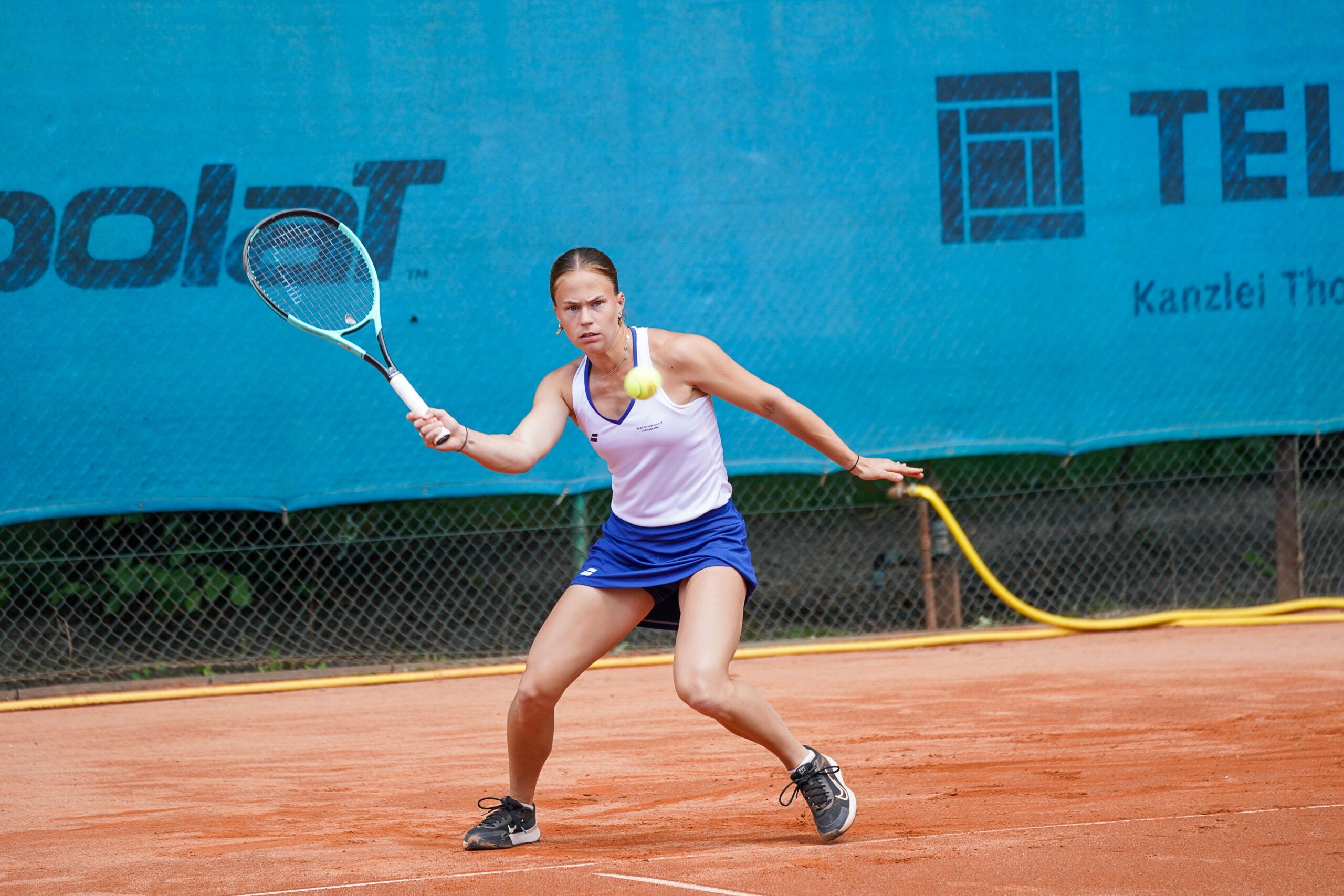 Tennisspielerin schlägt Vorhand auf Sandplatz