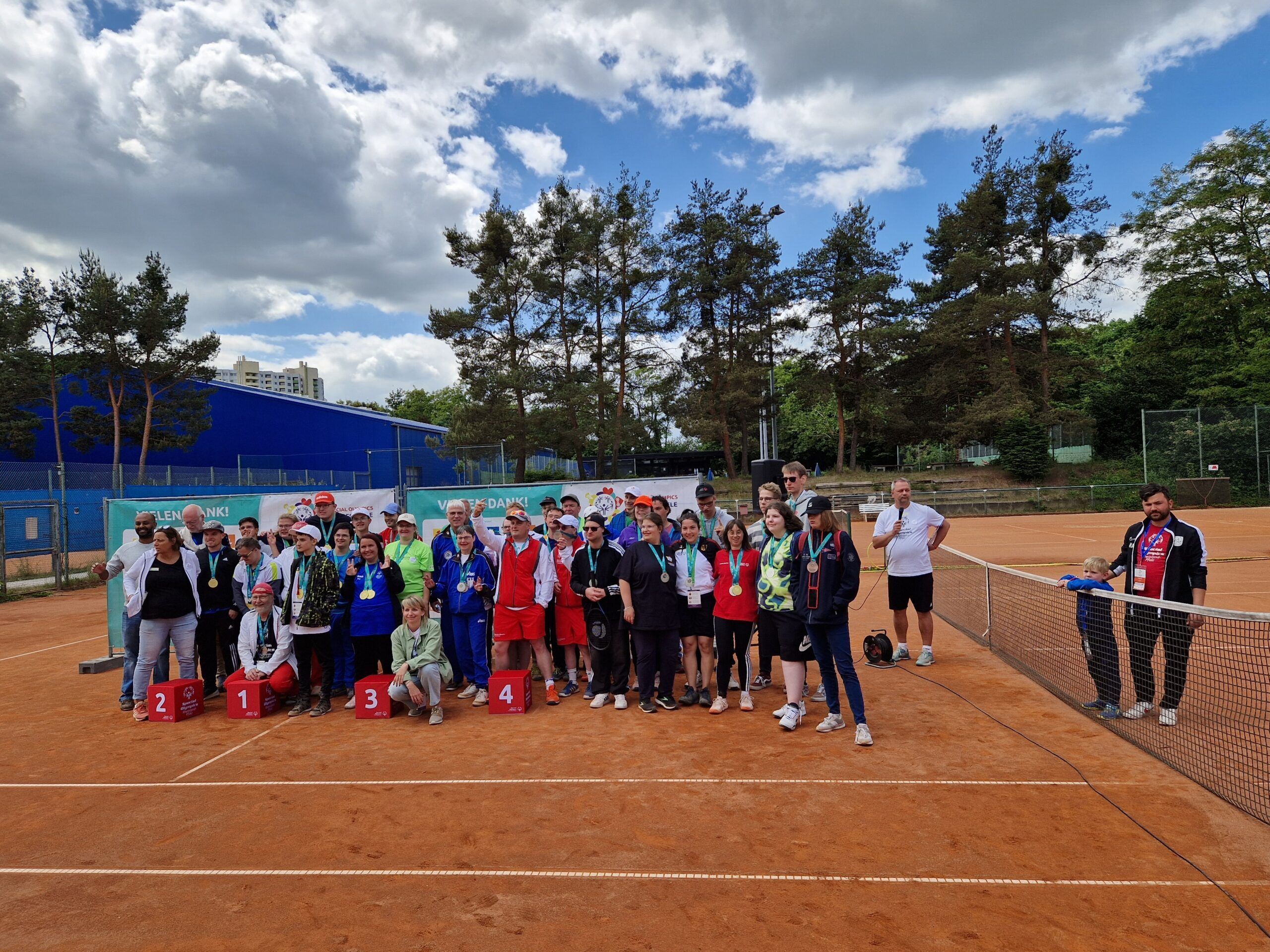 Siegerehrung auf Tennisplatz mit großer Teilnehmergruppe