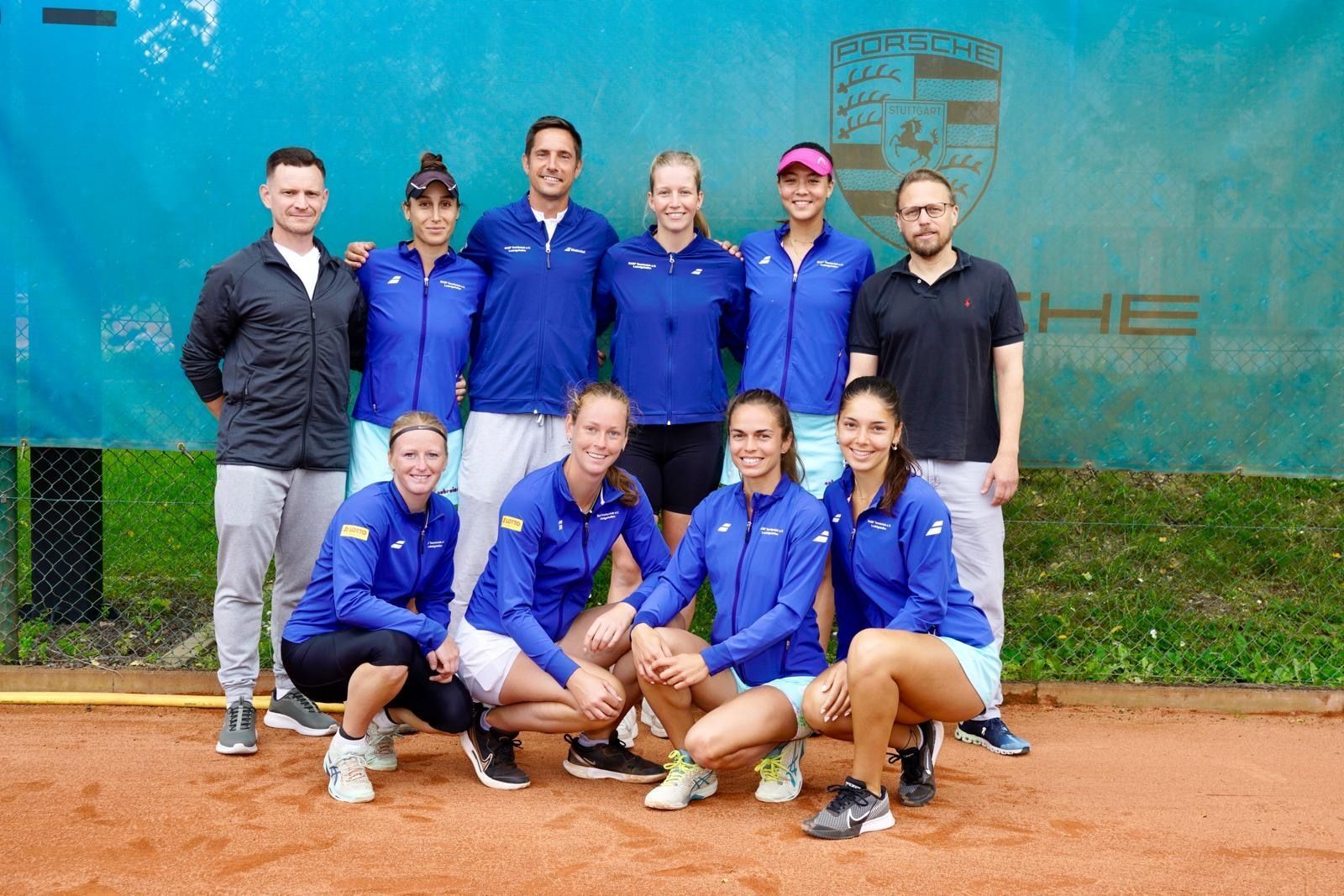 Tennisteam in blauen Jacken auf Sandplatz