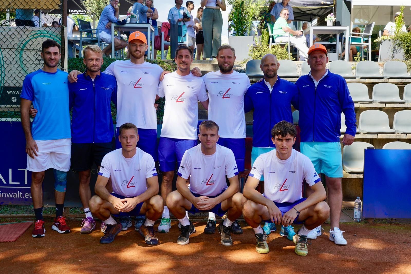 Tennismannschaft posiert auf Sandplatz vor Zuschauern