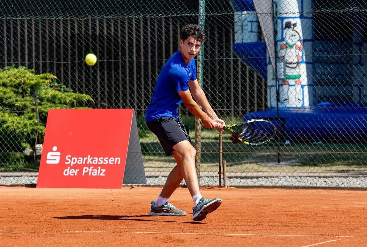 Tennisspieler schlägt Ball auf Sandplatz
