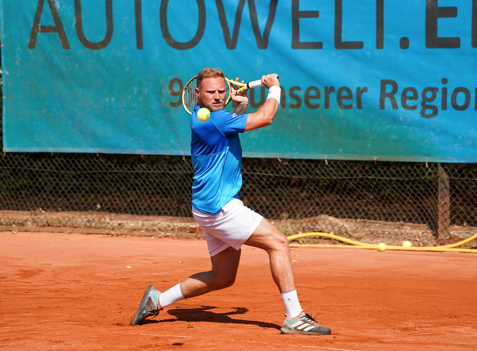 Tennisspieler schlägt Rückhand auf Sandplatz