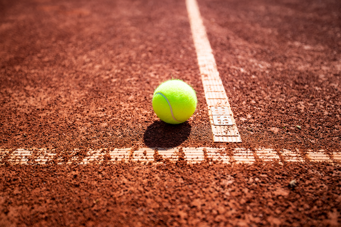 Tennisball auf Sandplatz nahe der Linie
