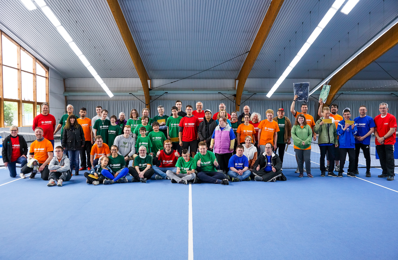 Gruppenfoto in Sporthalle mit bunten BASF-Shirts