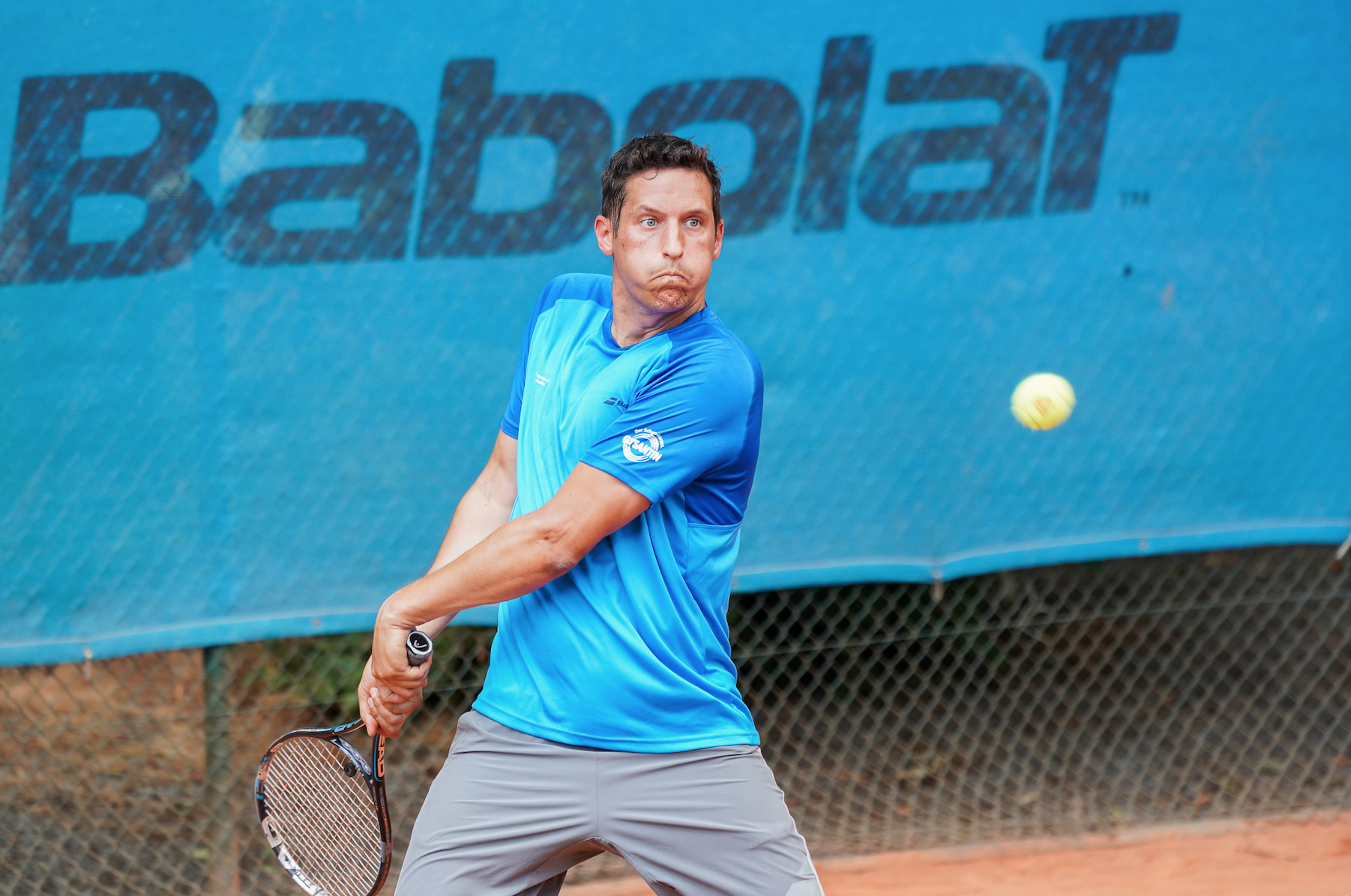 Tennisspieler beim Rückhandschlag auf Sandplatz