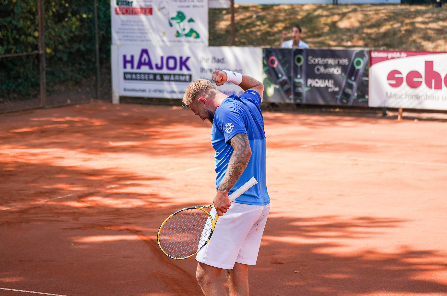 Tennisspieler jubelt auf Sandplatz mit Schläger