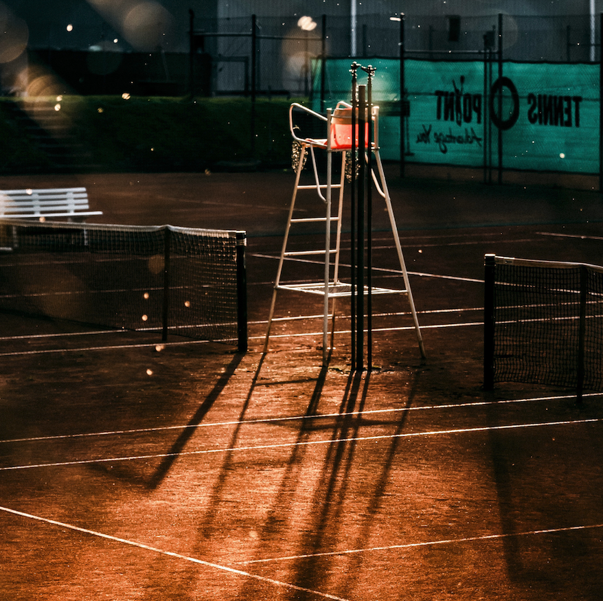 Leerer Tennisplatz bei Nacht mit Schiedsrichterstuhl