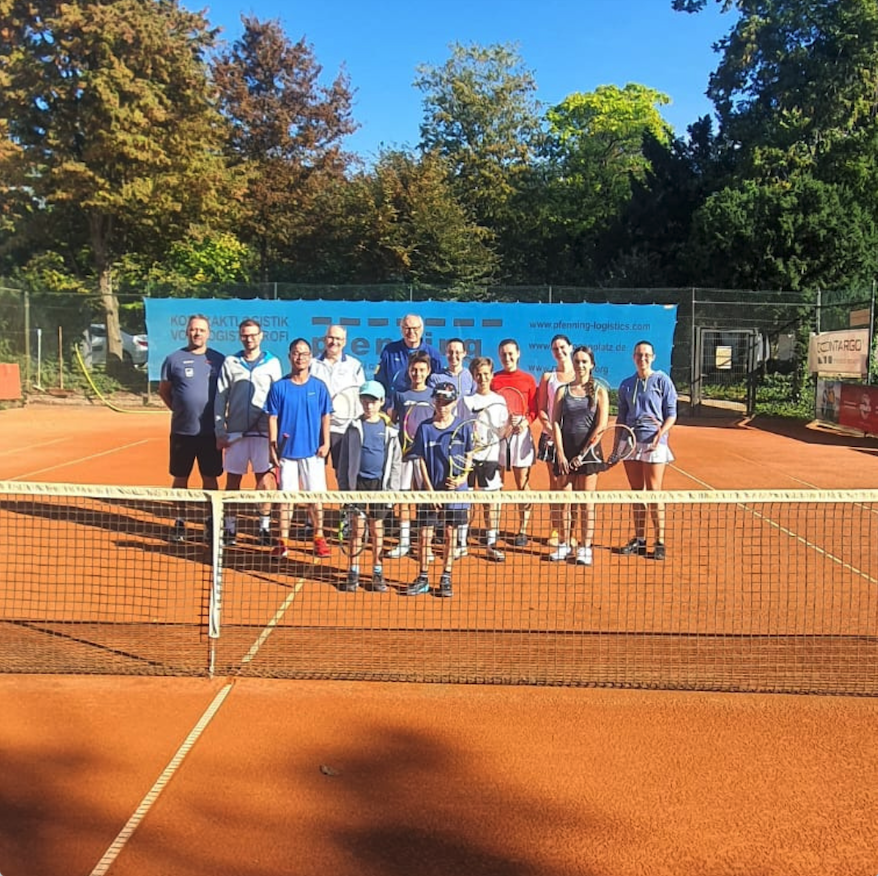Tennisgruppe auf Sandplatz hinter dem Netz