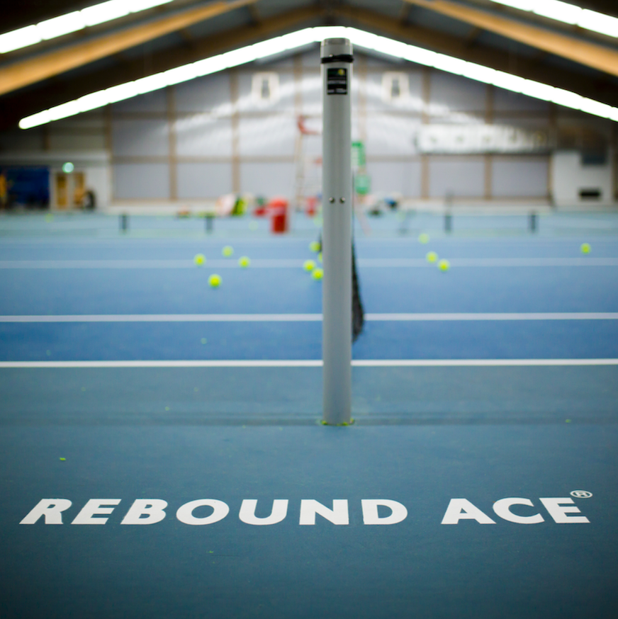 Tennishalle mit Netzpfosten und verstreuten Bällen