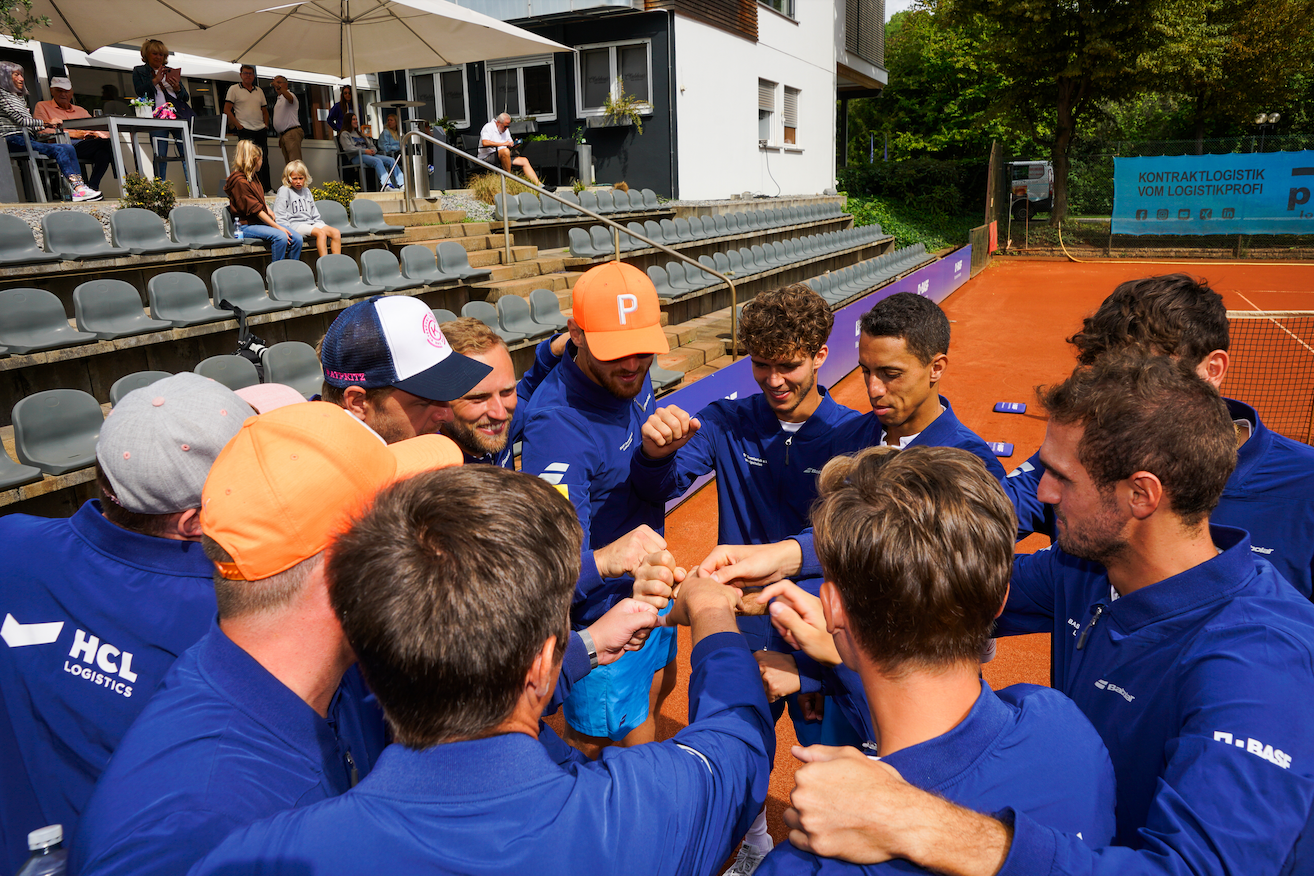 Tennisteam im Kreis auf Sandplatz