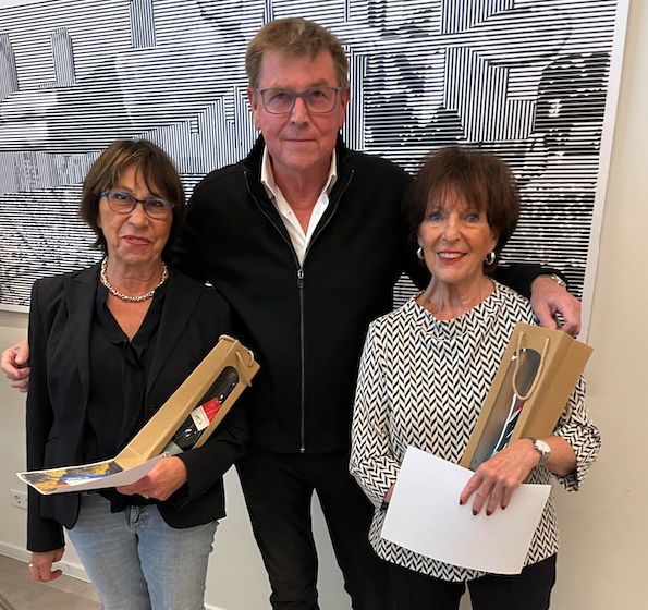 Drei Personen mit Geschenken vor Kunstwerk