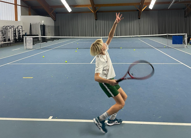 Kind beim Tennisaufschlag in der Halle
