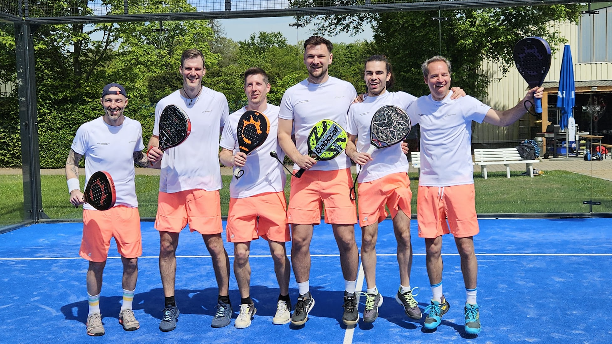 Sechs Männer mit Padel-Schlägern auf Outdoor-Platz
