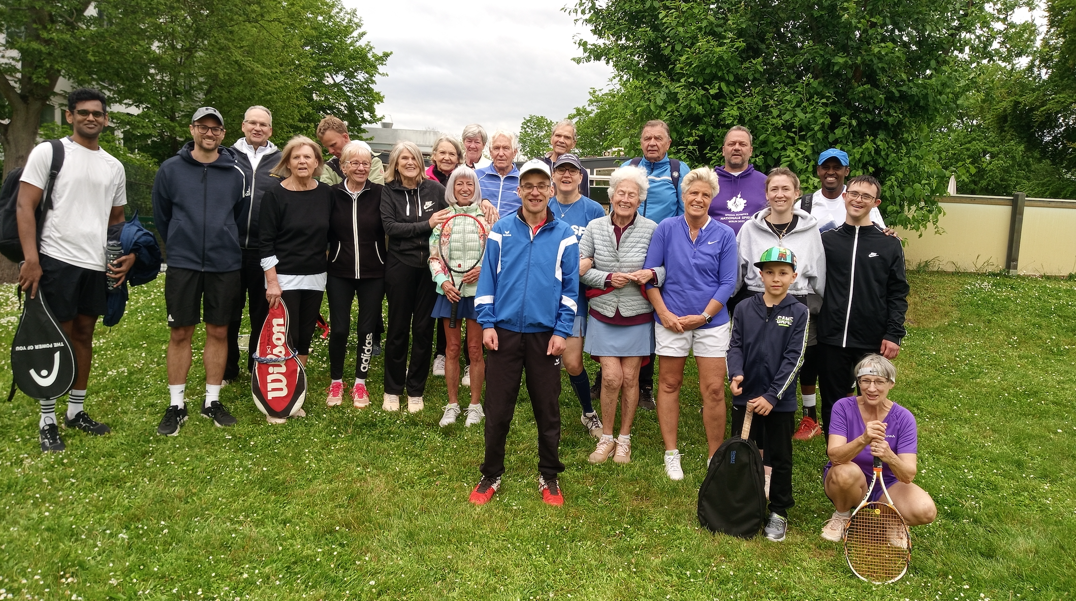 Große Tennisgruppe mit Schlägern auf Rasenfläche