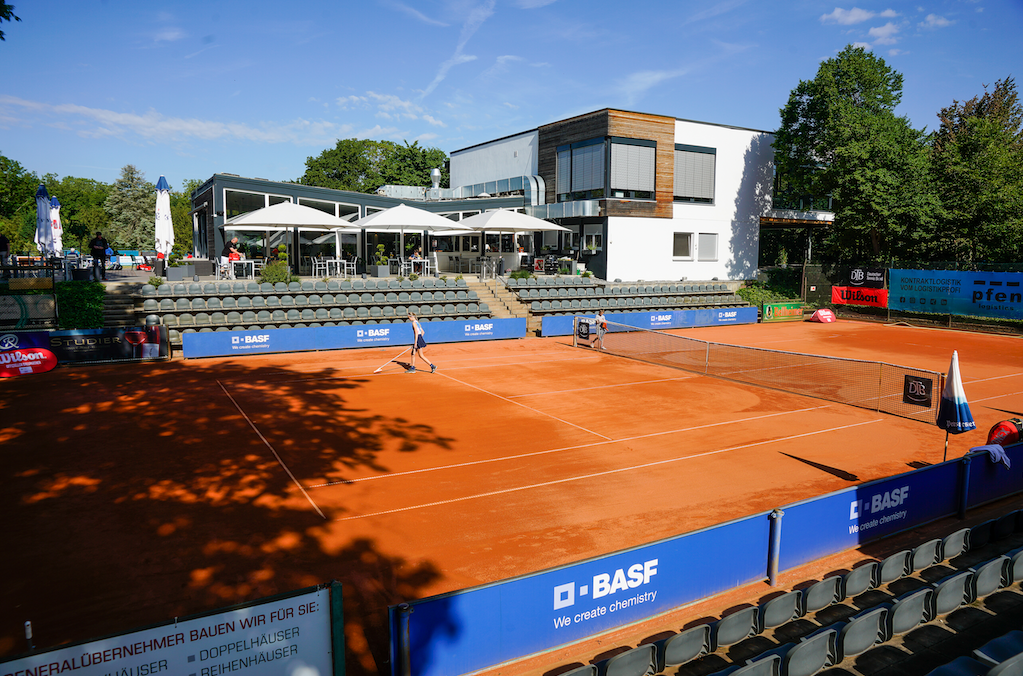 Tennisplatz mit Clubhaus und Zuschauerrängen
