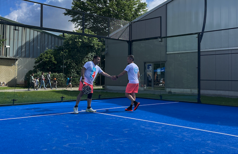Zwei Männer geben sich die Hand auf Padelplatz