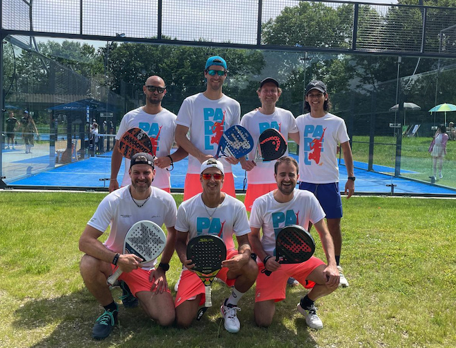 Sieben Männer mit Padel-Schlägern vor Padelplatz