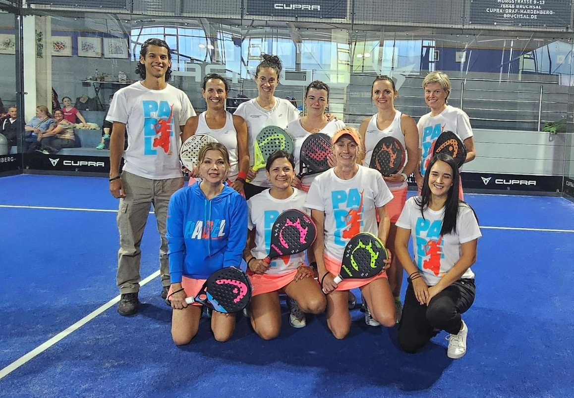 Padel-Team posiert mit Schlägern auf Indoor-Court