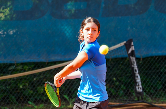 Mädchen schlägt Tennisball auf Outdoor-Platz