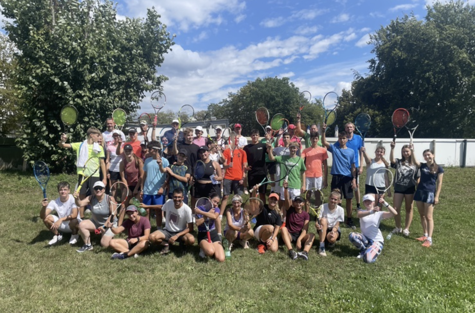 Große Tennisgruppe mit Schlägern auf Rasen