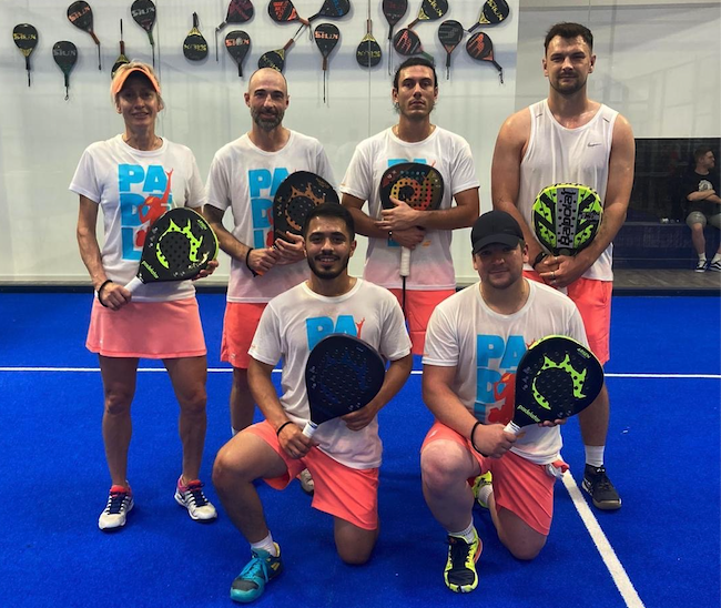 Sechs Spieler mit Padel-Schlägern auf Hallenplatz