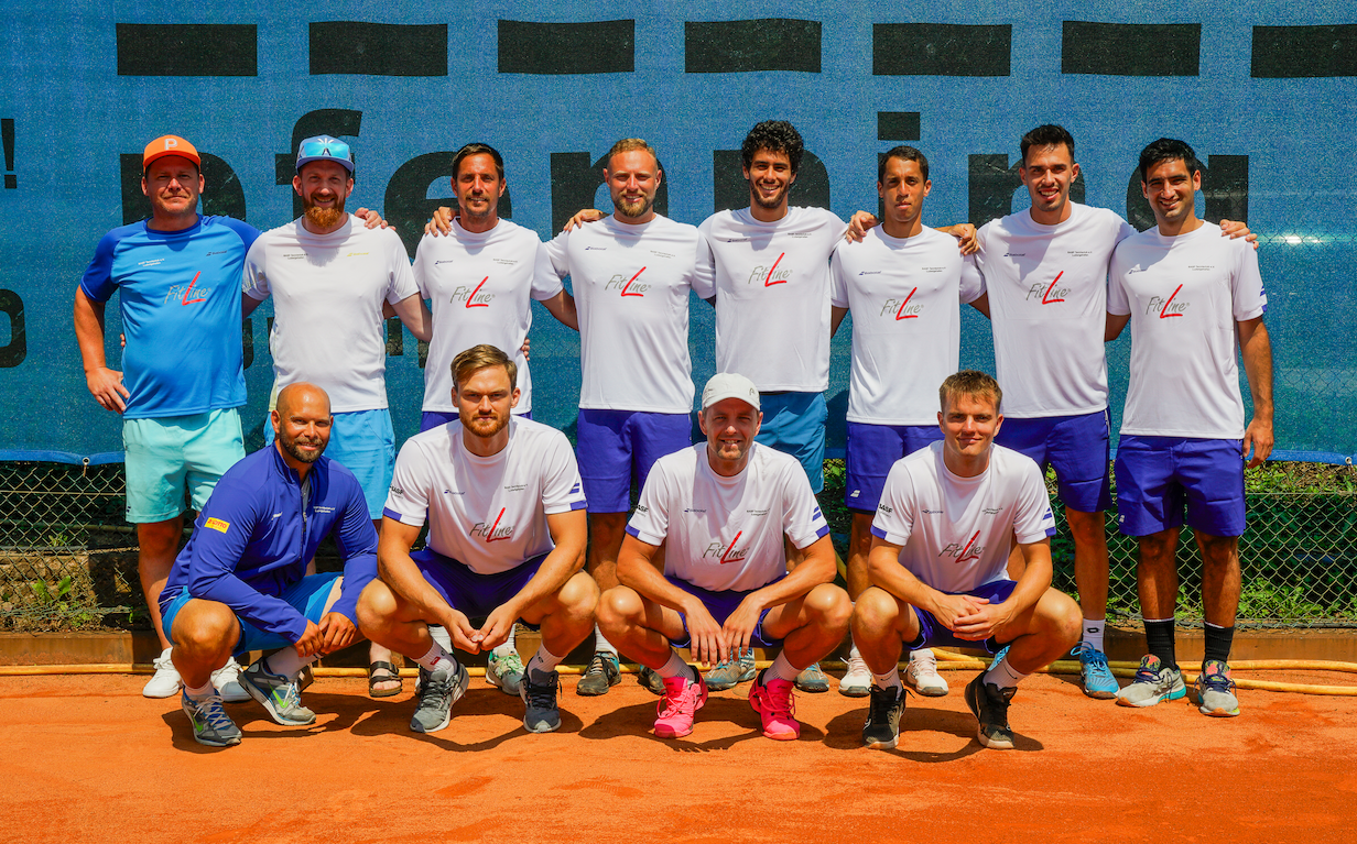 Tennismannschaft posiert auf Sandplatz im Teamoutfit