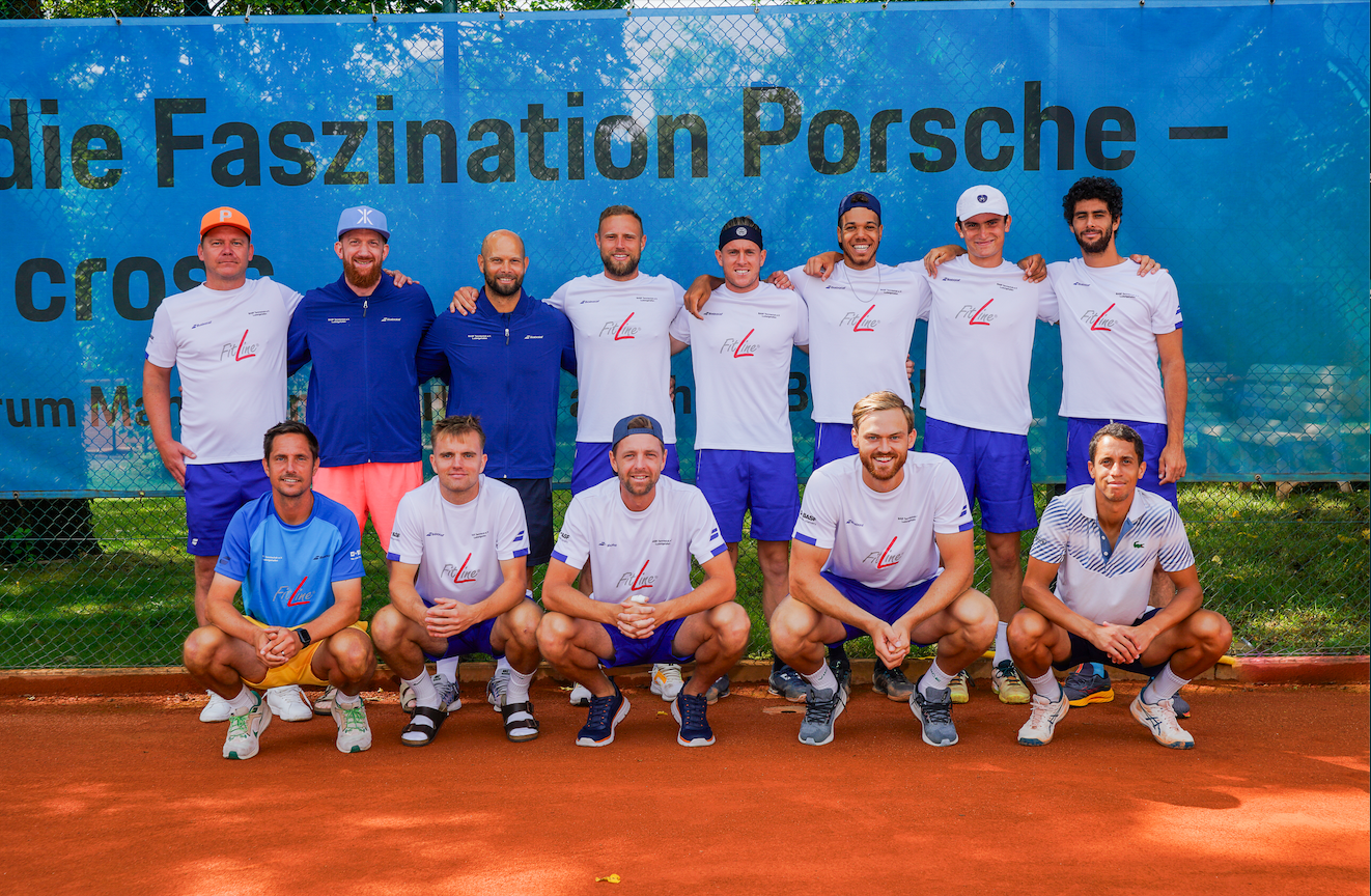 Tennismannschaft posiert auf Sandplatz vor Banner