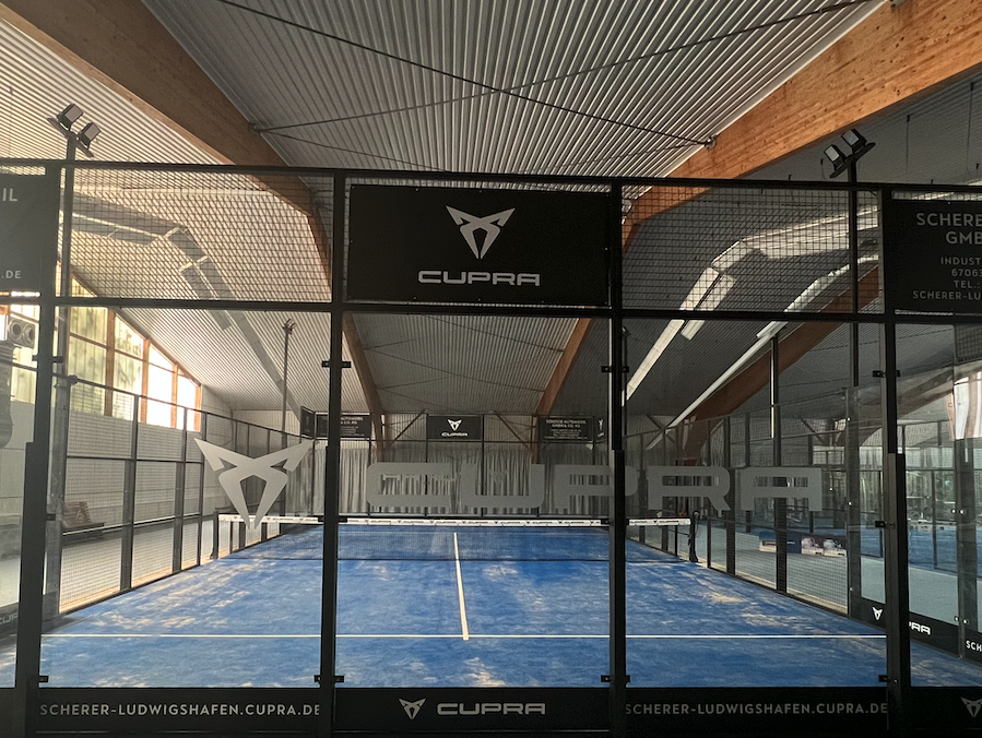Indoor-Padelplatz mit CUPRA-Branding und Glaswänden