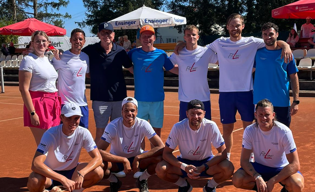 Tennisteam posiert auf Sandplatz bei Sonnenschein